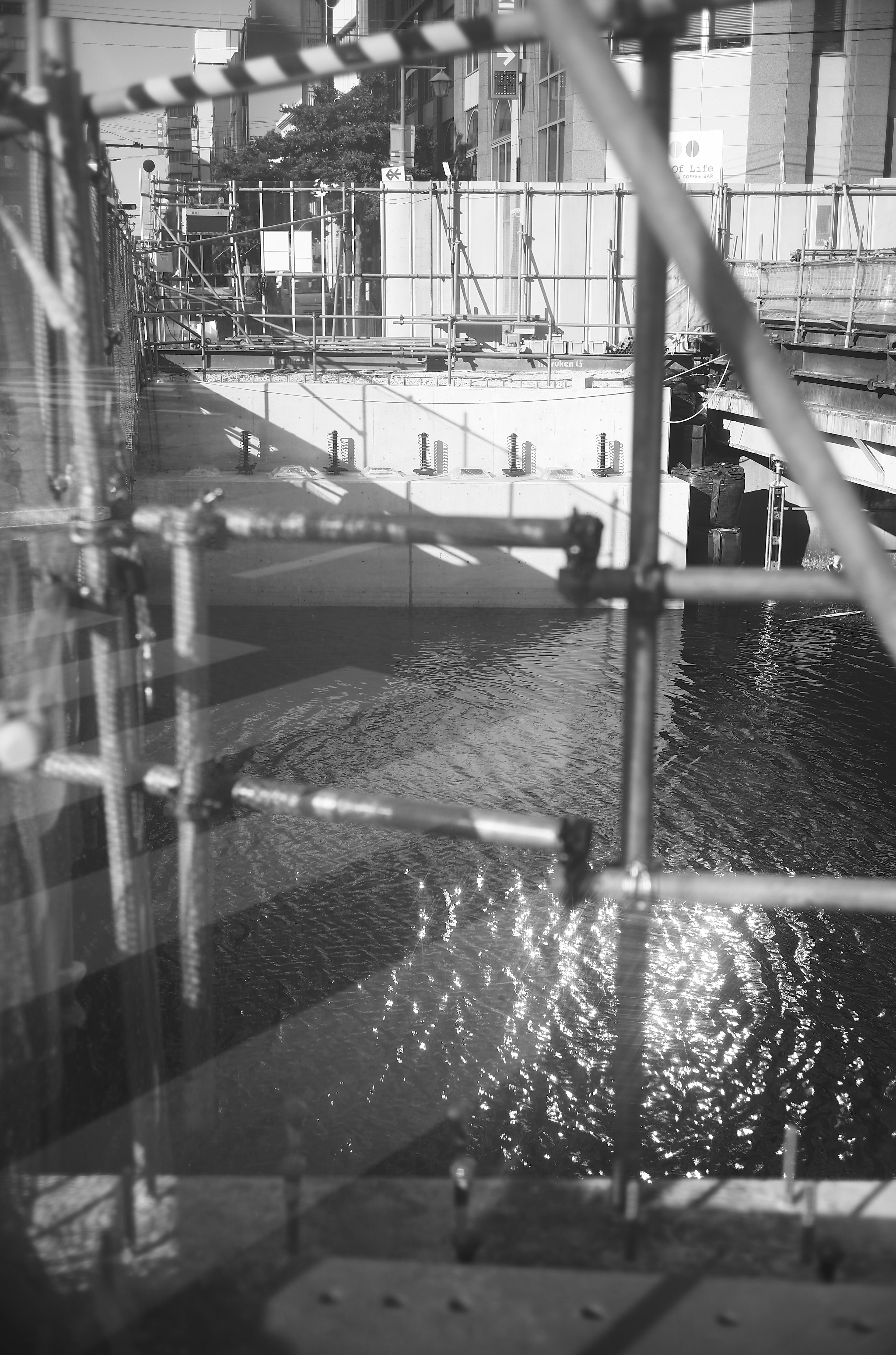 Black and white image of a construction site with scaffolding and water surface