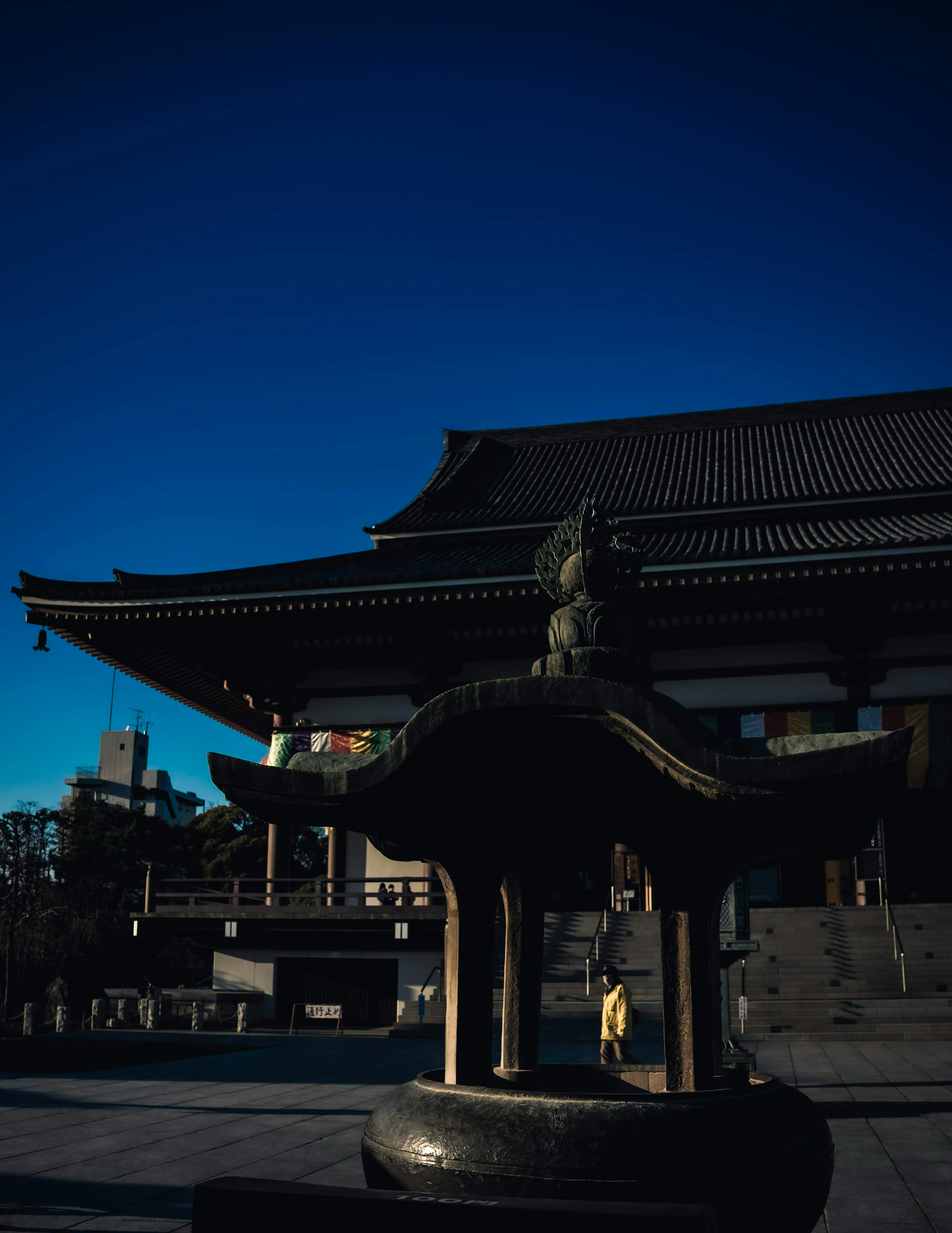 Traditional temple with a water basin sculpture under a blue sky