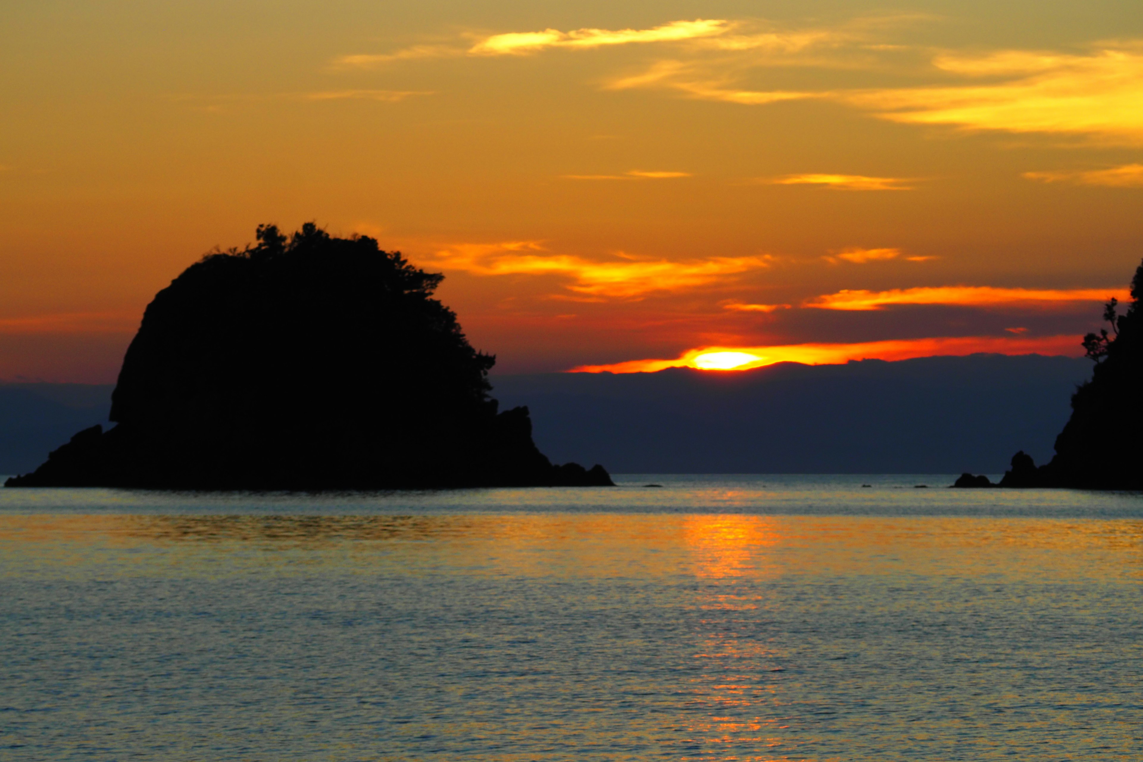 Sonnenuntergang über dem Ozean mit silhouettierten Inseln