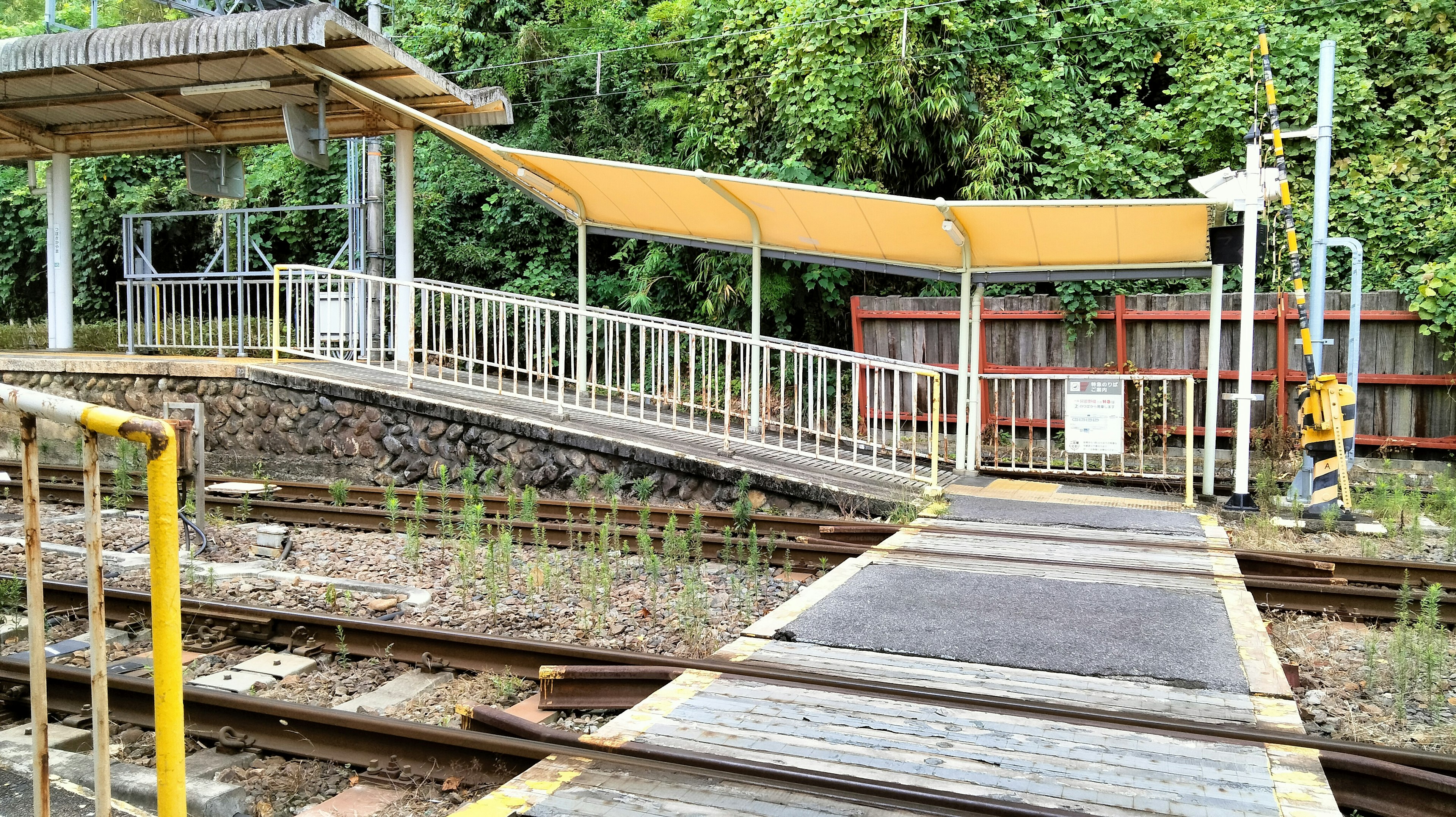 Ansicht einer Bahnhofsplattform mit einem gelben Vordach und Gleisen