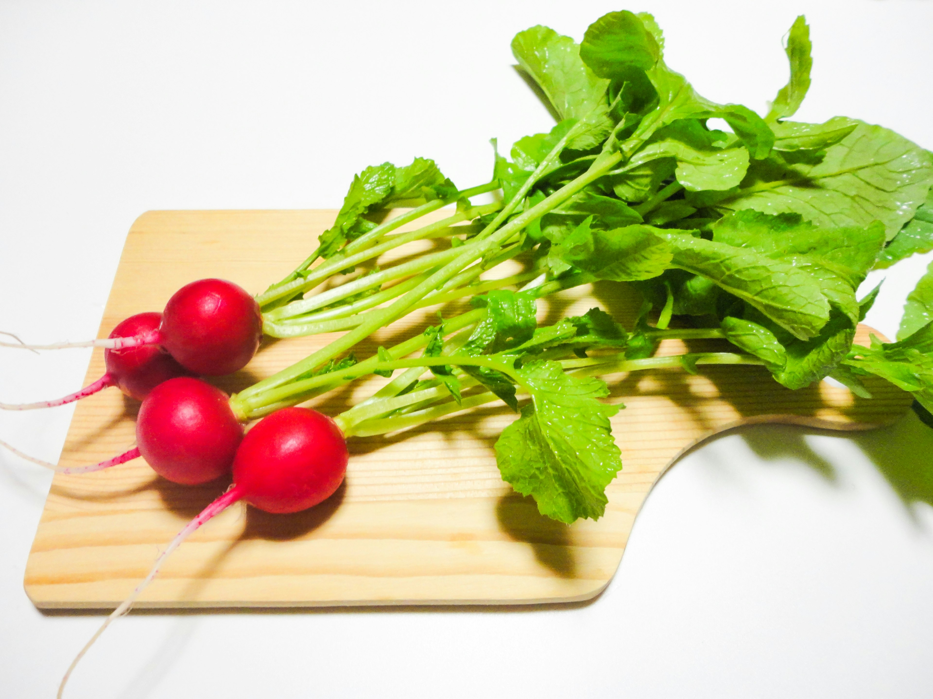 Radis rouges frais avec des feuilles vertes sur une planche à découper en bois