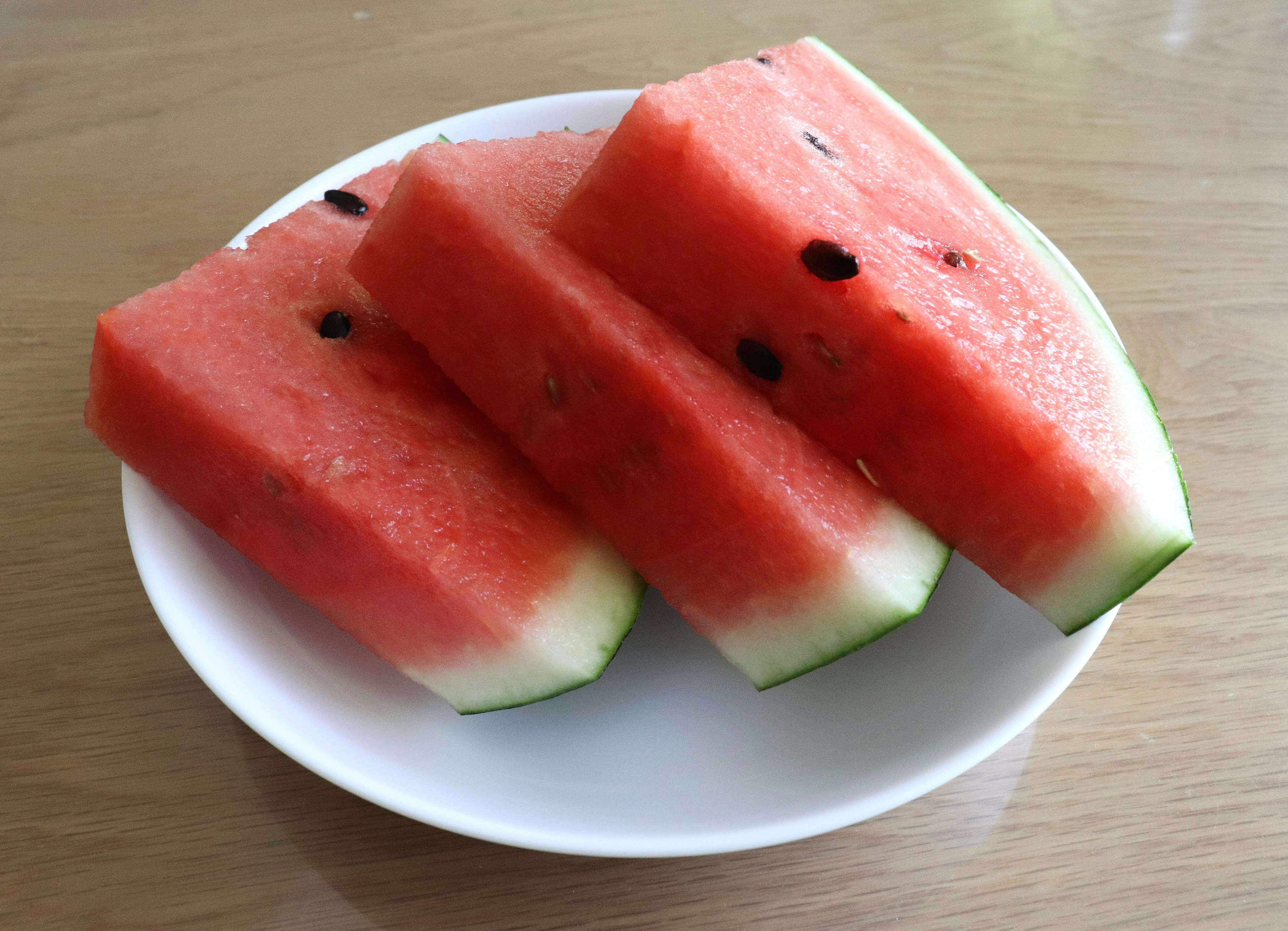 Three slices of watermelon arranged on a white plate