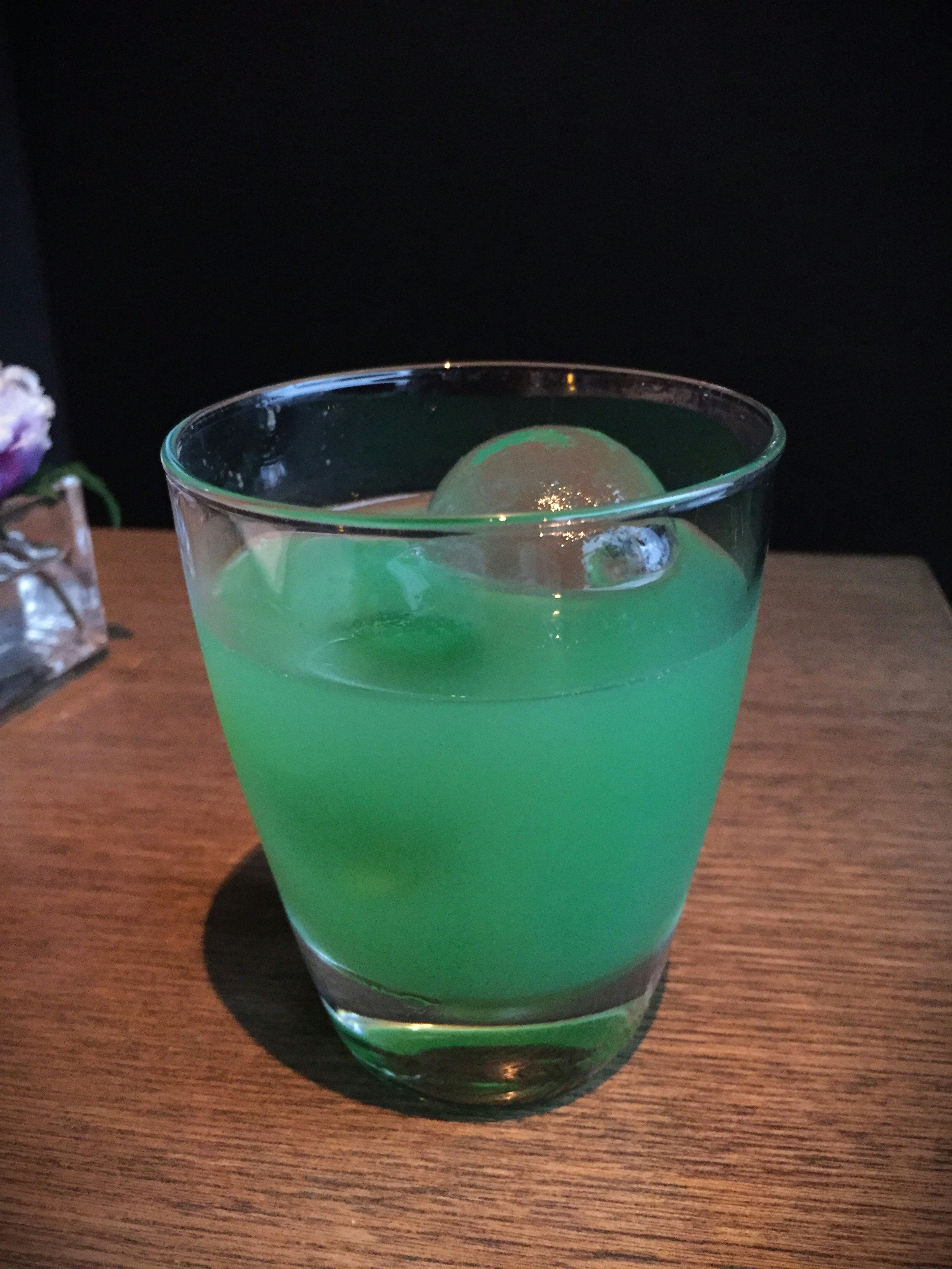 Green cocktail with ice in a glass