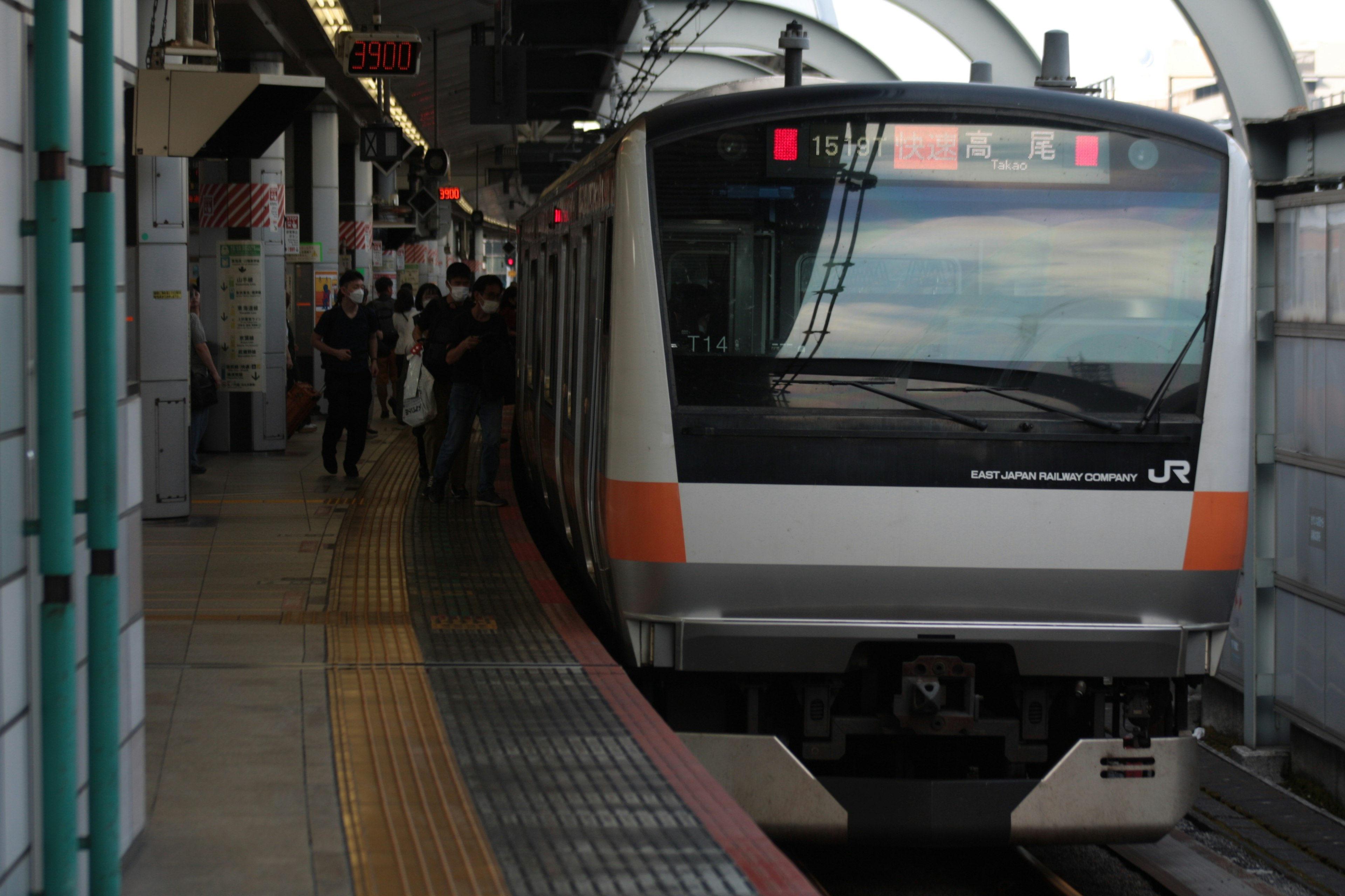 Treno JR in stazione con passeggeri che salgono e scendono