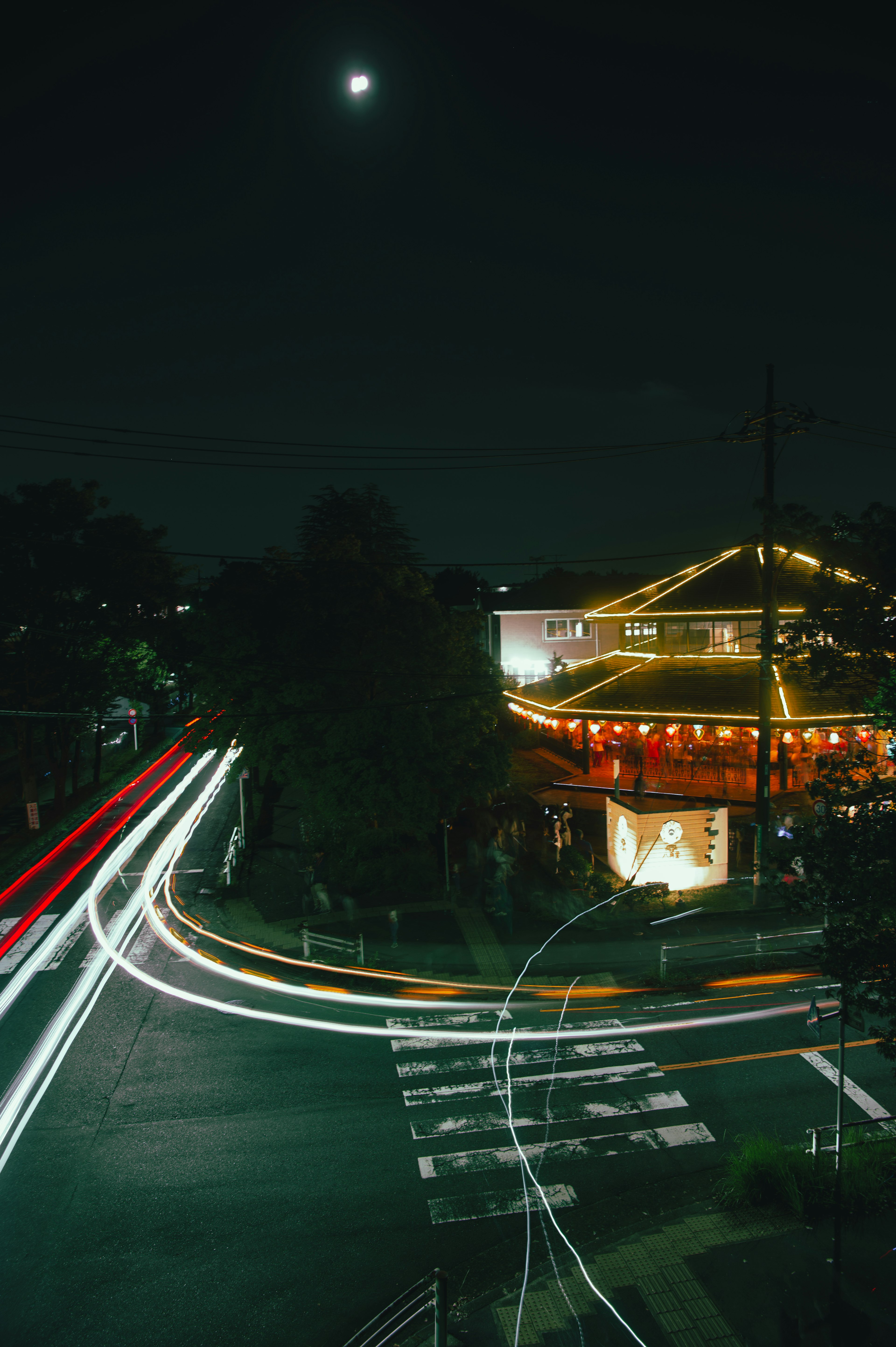 Bright building at a street corner with flowing car lights at night