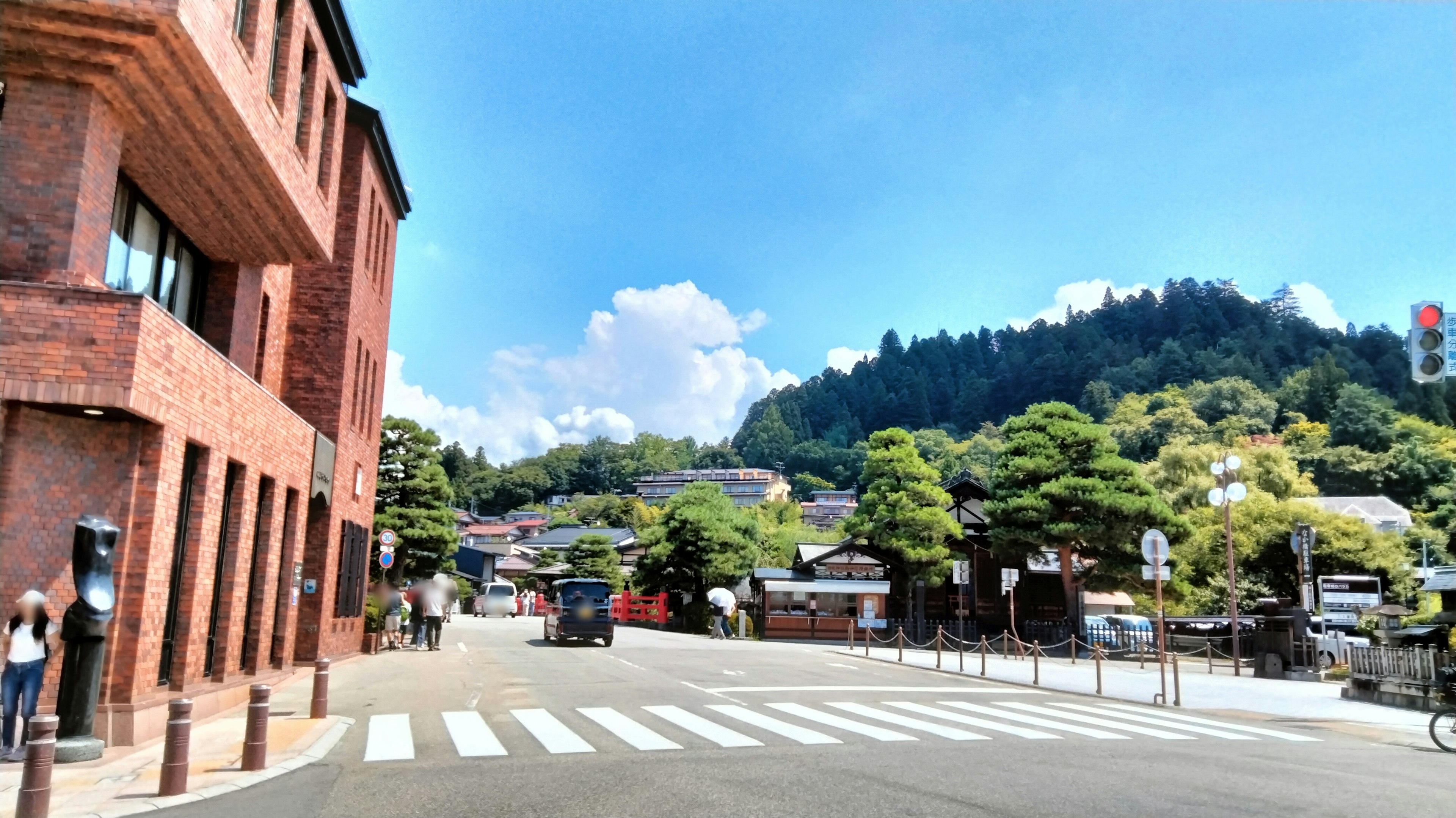 Städtische Landschaft mit Backsteingebäude und Zebrastreifen vor Hügeln und blauem Himmel