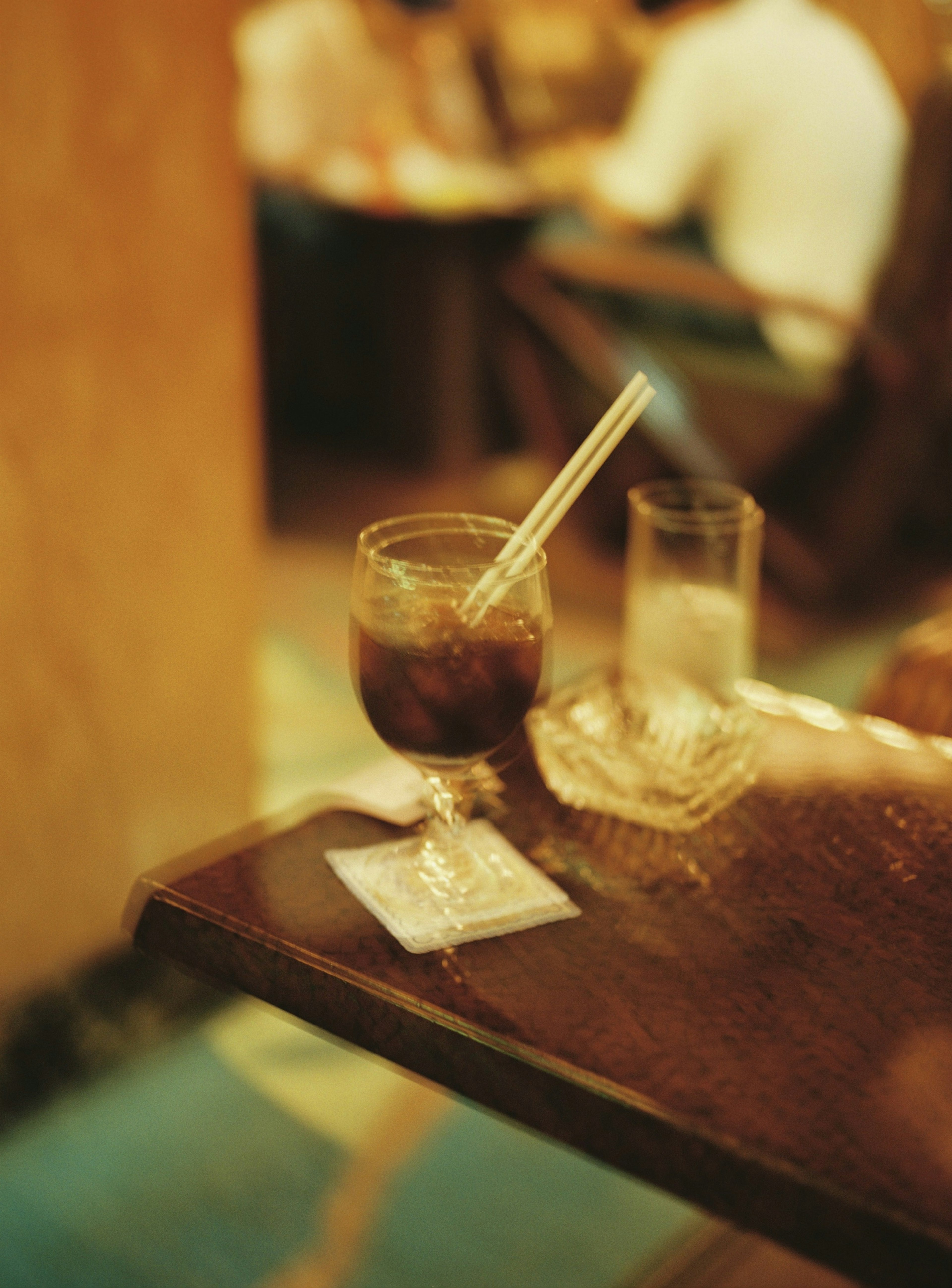 Un vaso de cóctel con una pajita y un vaso de agua sobre una mesa de madera