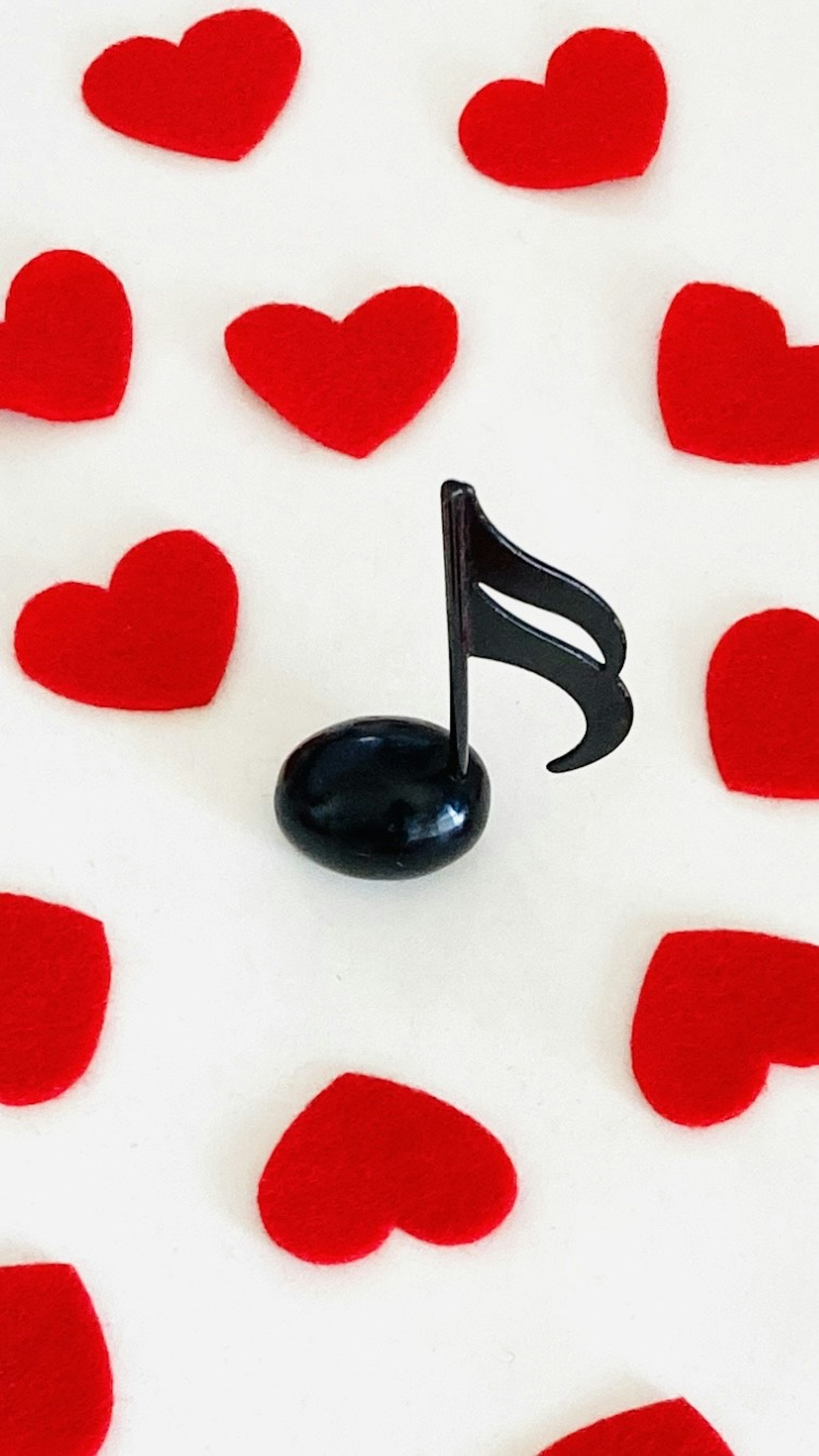 A black musical note surrounded by red hearts