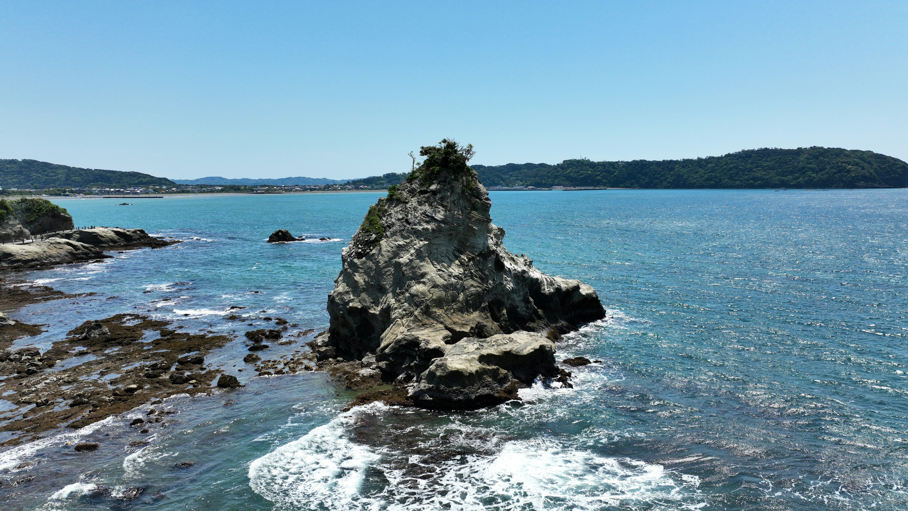 Rocky outcrop surrounded by blue ocean with gentle waves