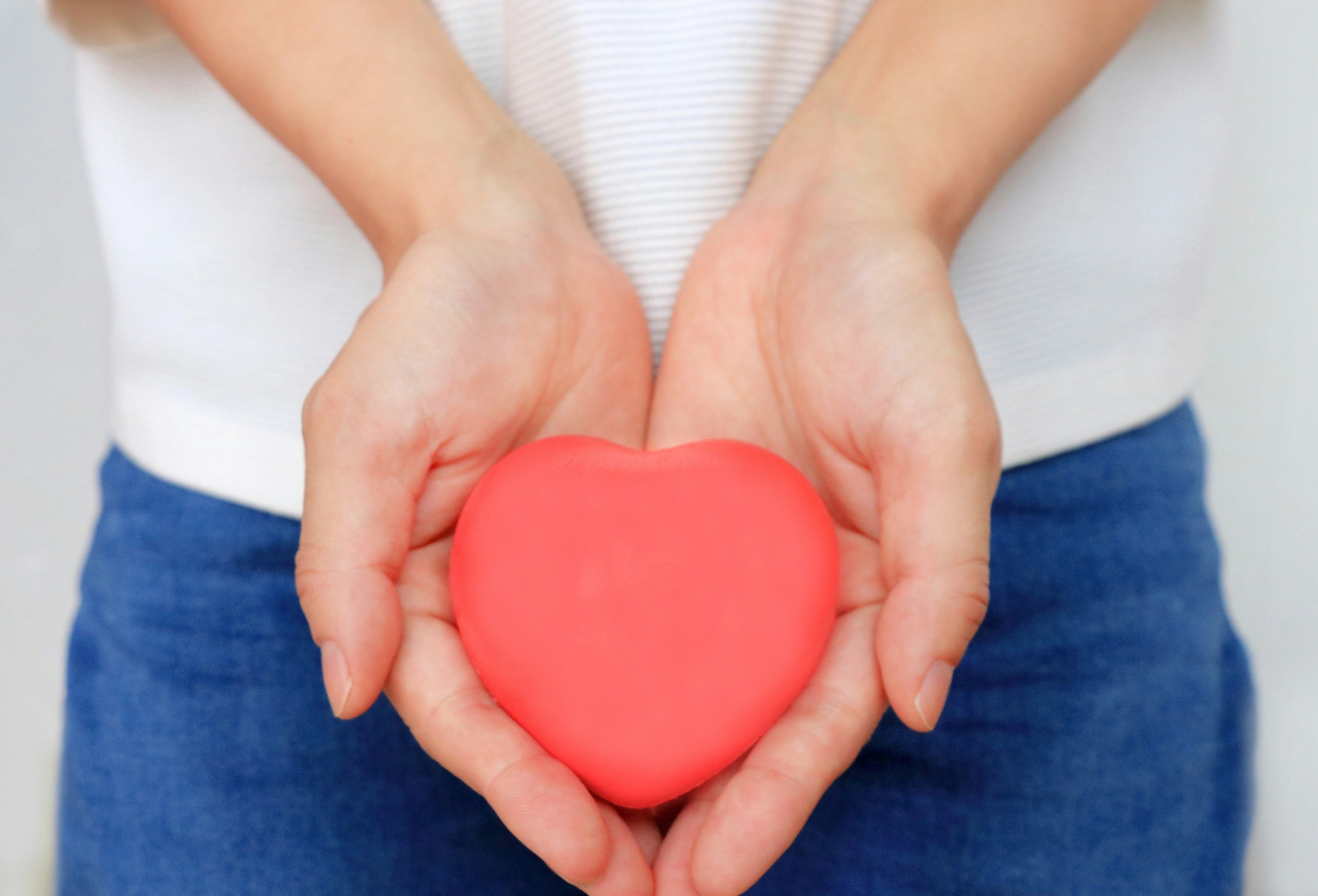 Mani che tengono un oggetto a forma di cuore rosso