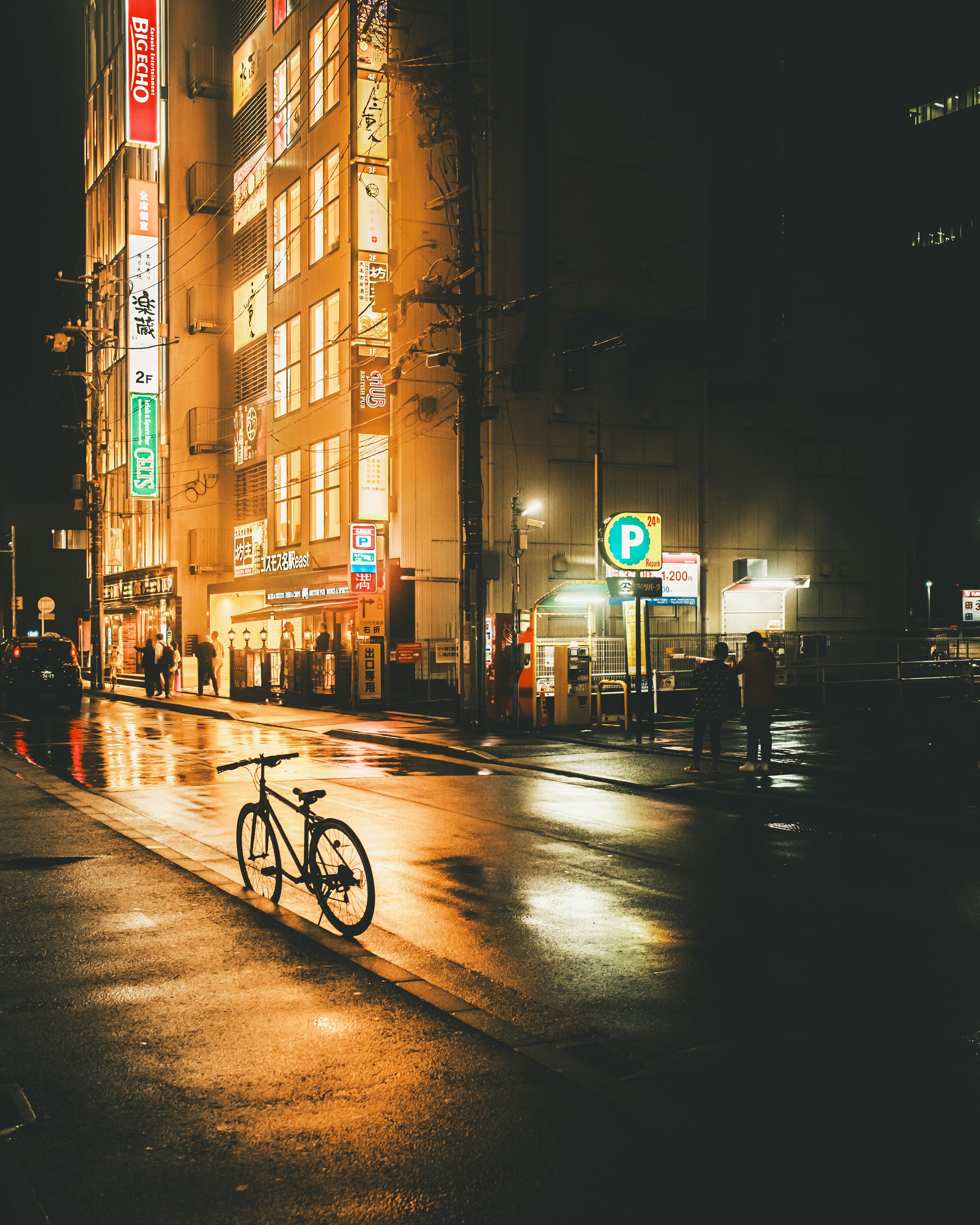 Bicicletta in piedi su una strada bagnata che riflette le luci della città di notte