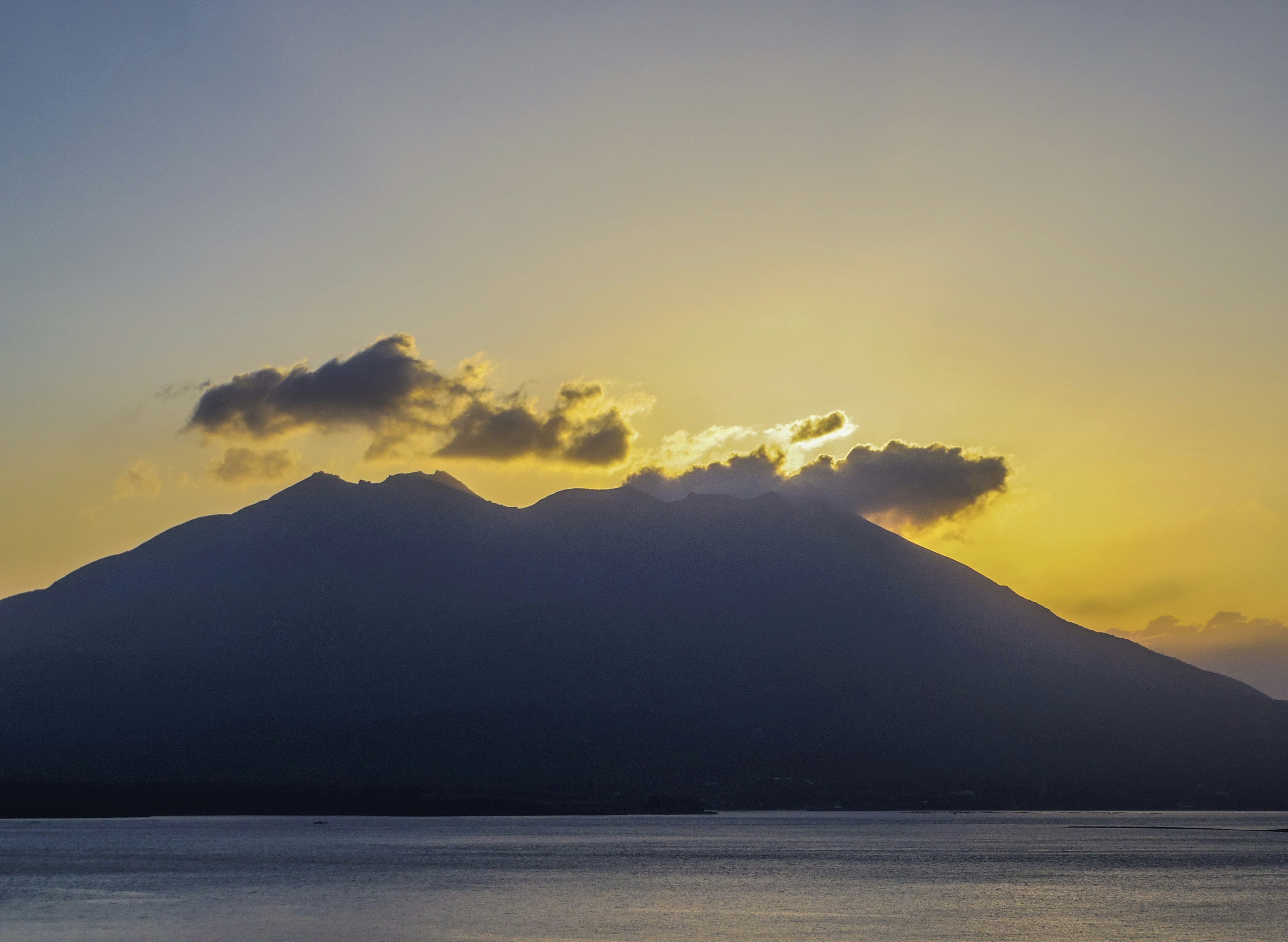 Silueta de una montaña al atardecer con mar tranquilo