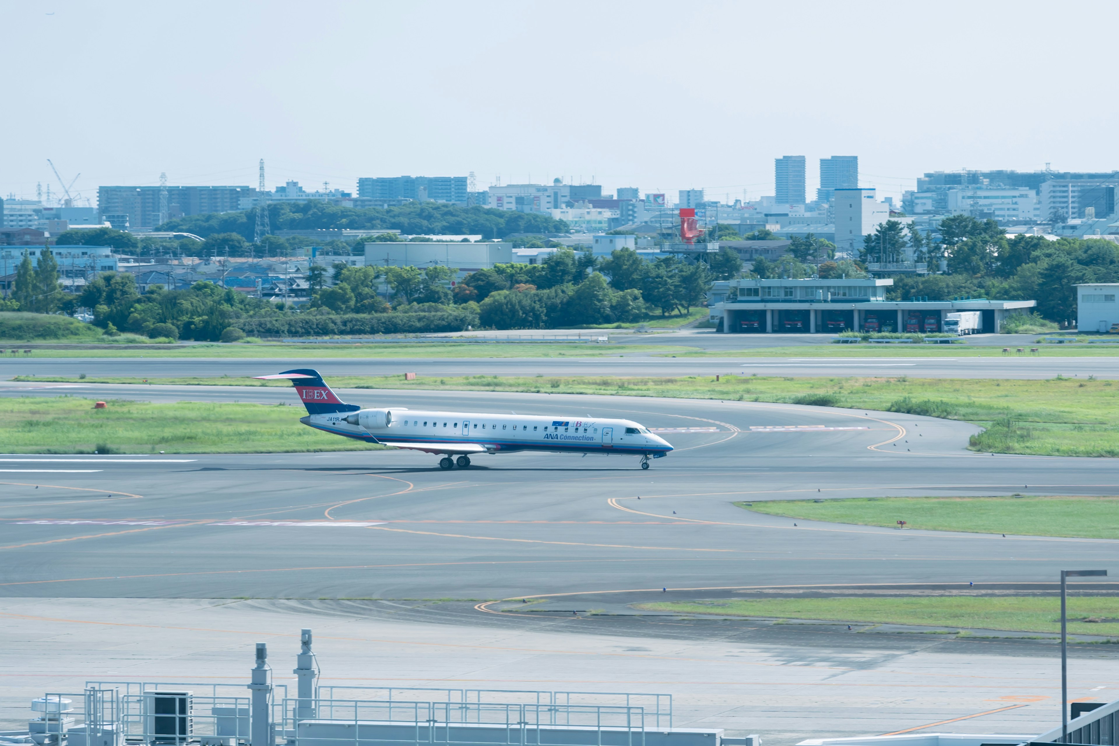 Aereo che scivola sulla pista dell'aeroporto con paesaggio urbano sullo sfondo