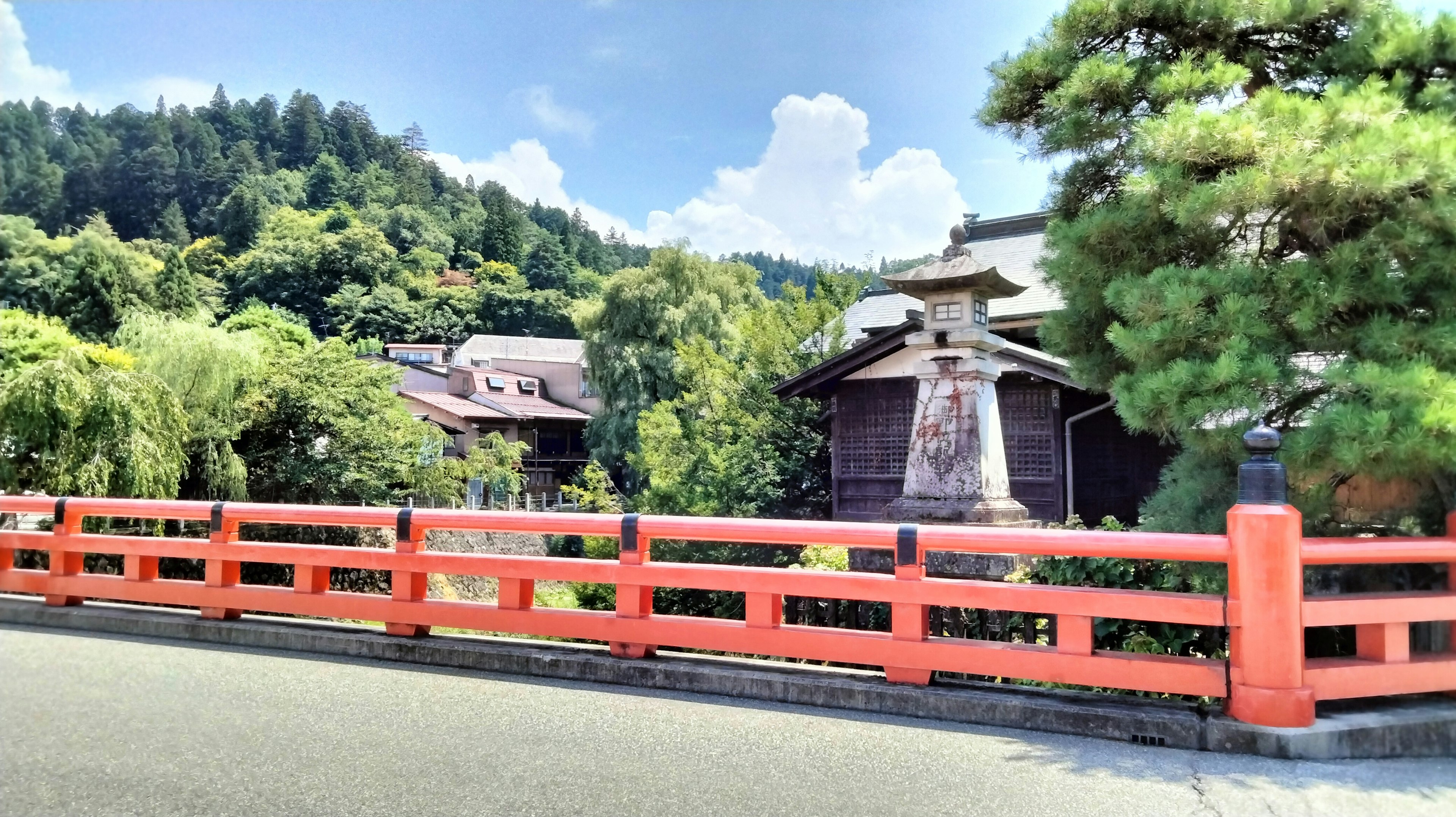 Malersiche Aussicht mit einer roten Brücke umgeben von grünen Hügeln und traditionellen Gebäuden