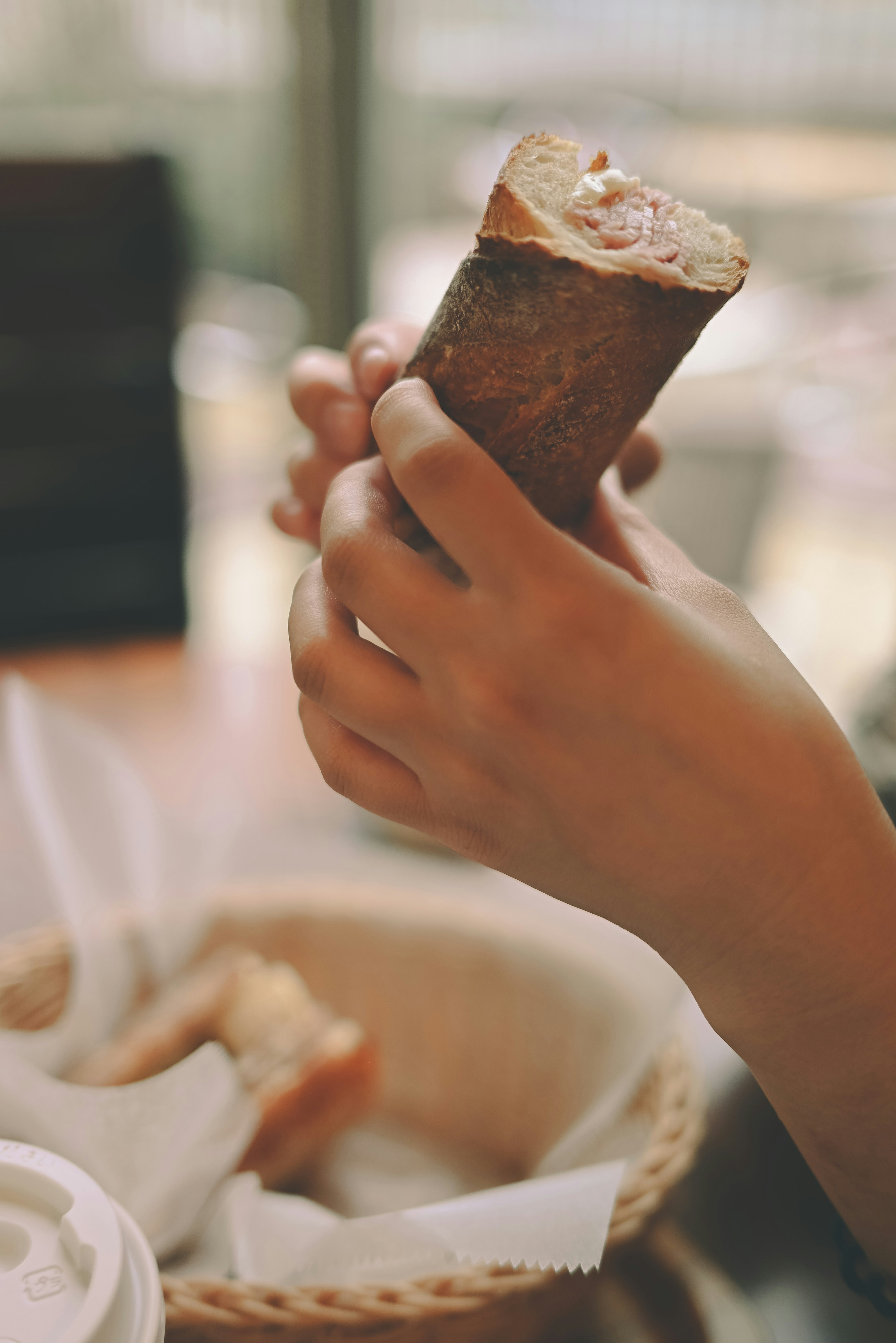 A close-up of hands holding a piece of bread with a soft background