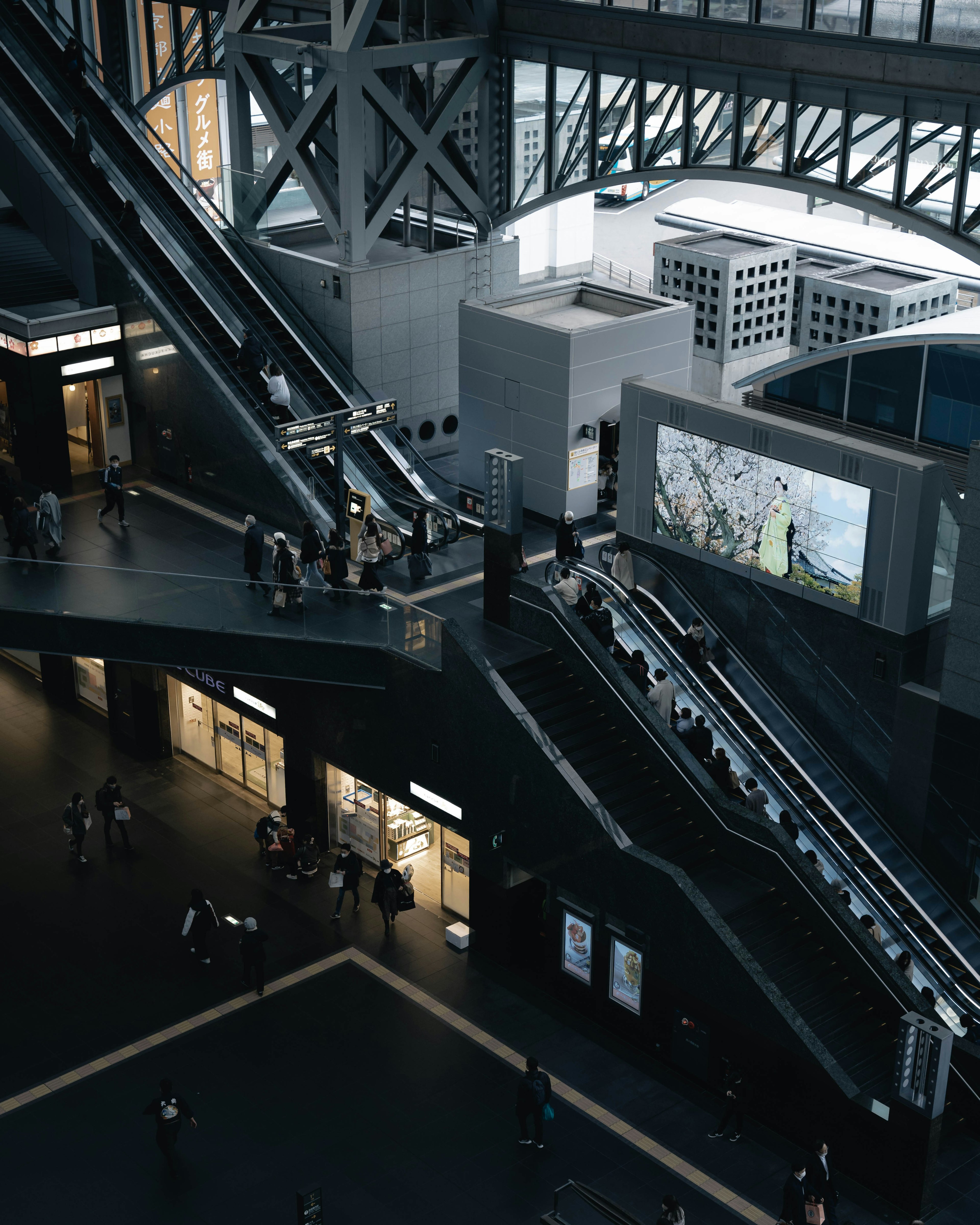 Vista interior de un espacio arquitectónico moderno con escaleras mecánicas y personas