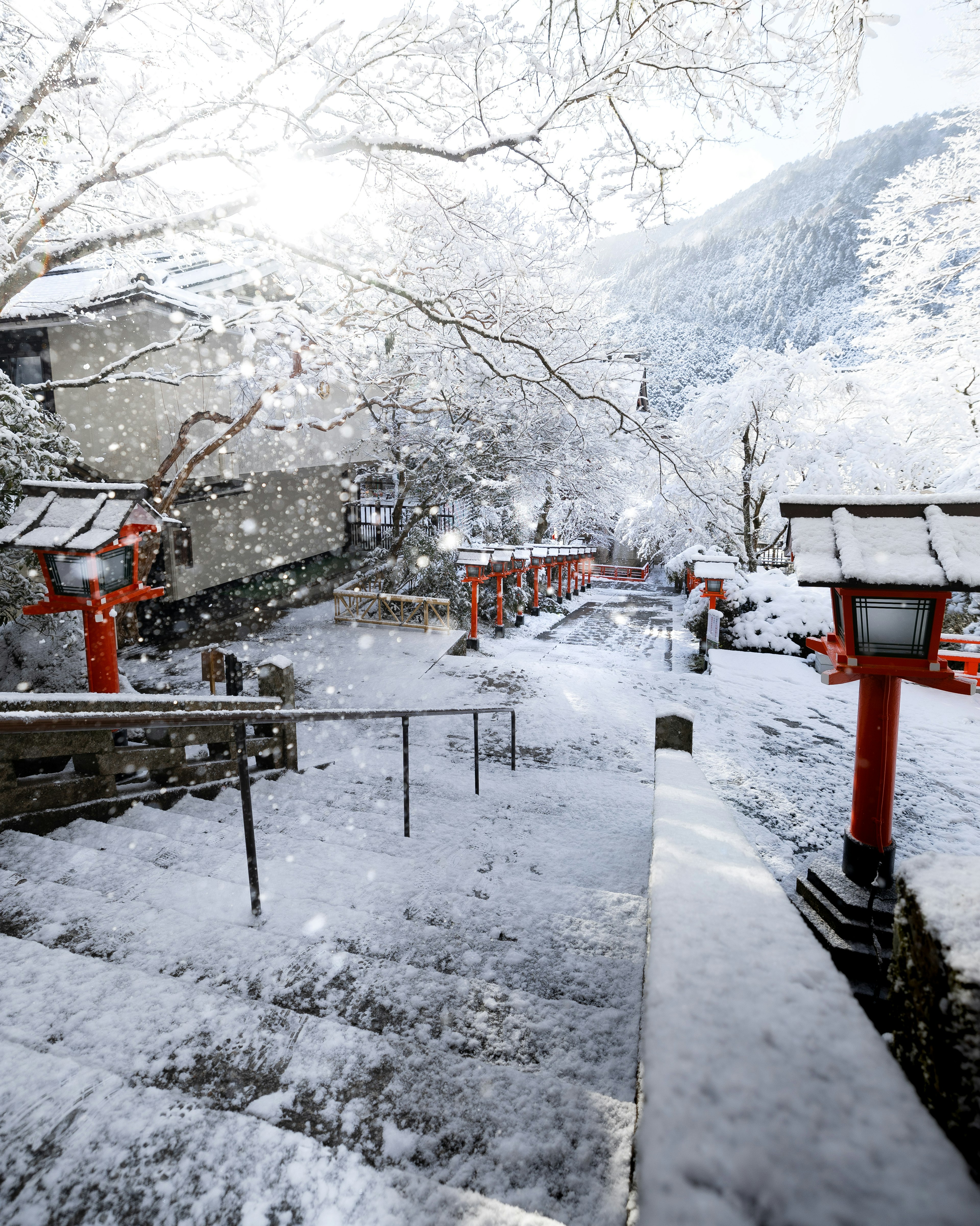 Snow-covered stairs with red lanterns in a serene landscape