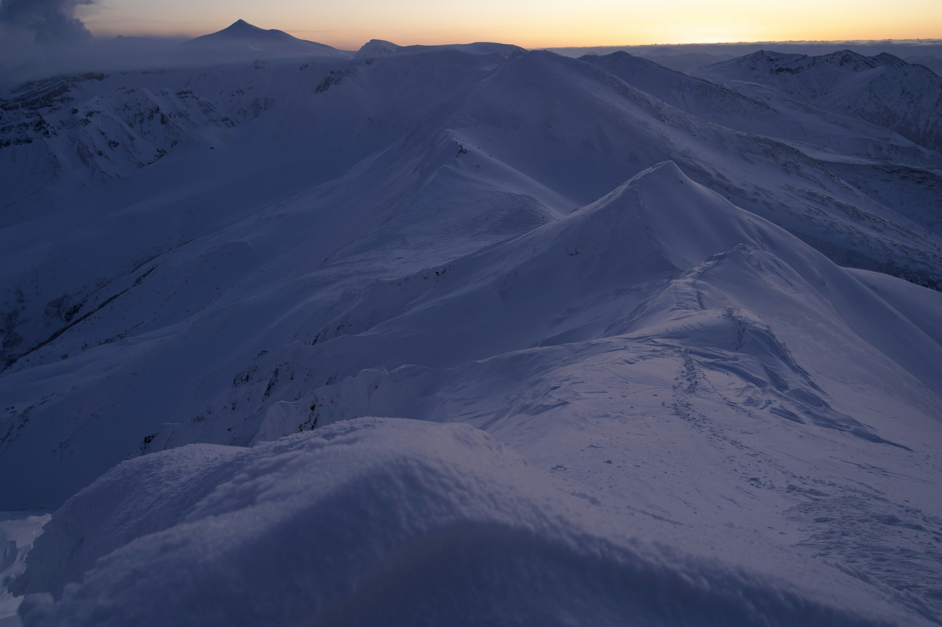 Paisaje montañoso cubierto de nieve con cielo al atardecer