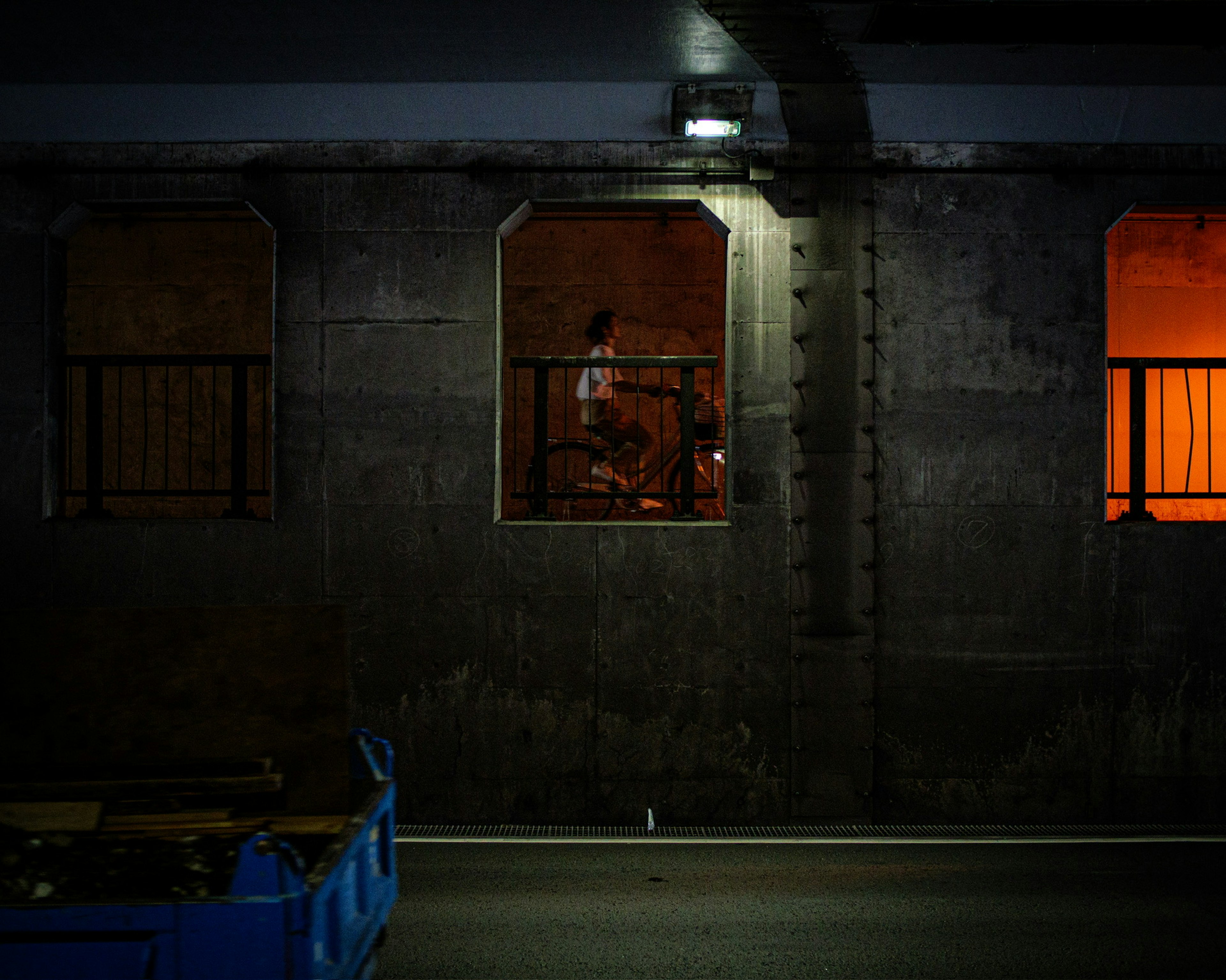 Person sichtbar durch ein orangefarbenes Fenster in einer dunklen Tunnelwand