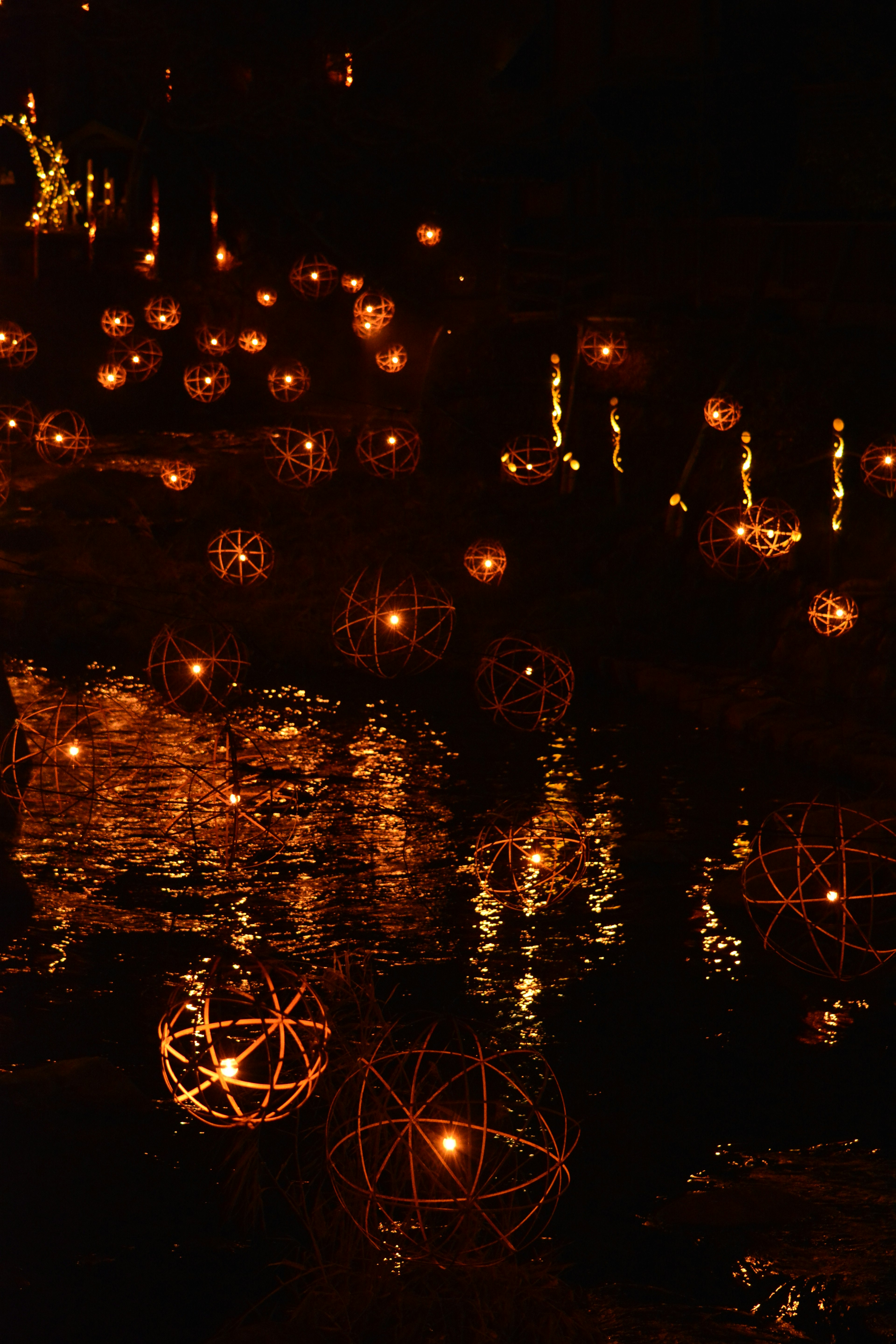 Une scène nocturne magique avec des orbes lumineux flottant sur l'eau et des reflets environnants