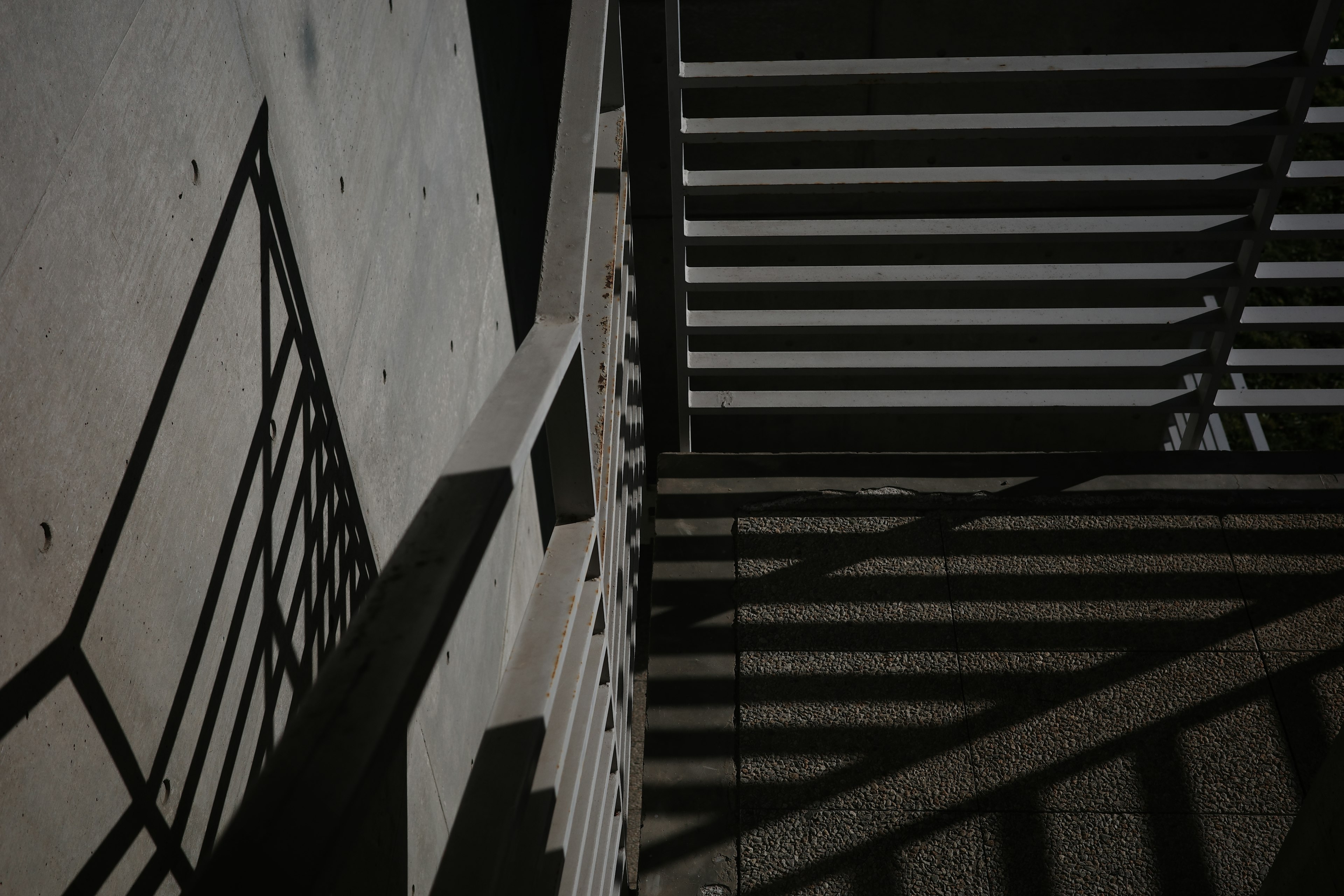 Escena nocturna con escaleras y sombras en una pared de concreto