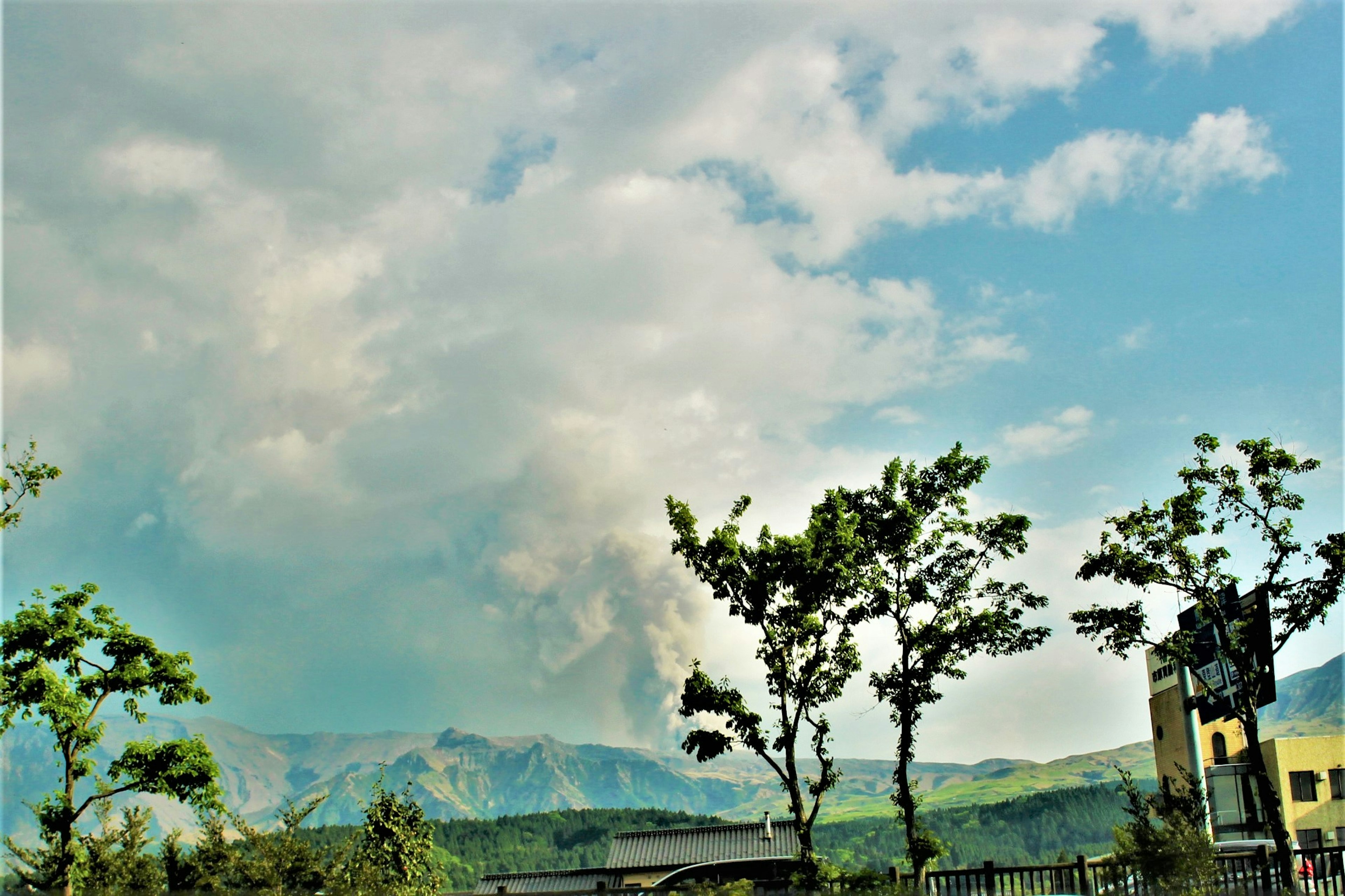 煙を上げる山と青い空に浮かぶ雲の風景