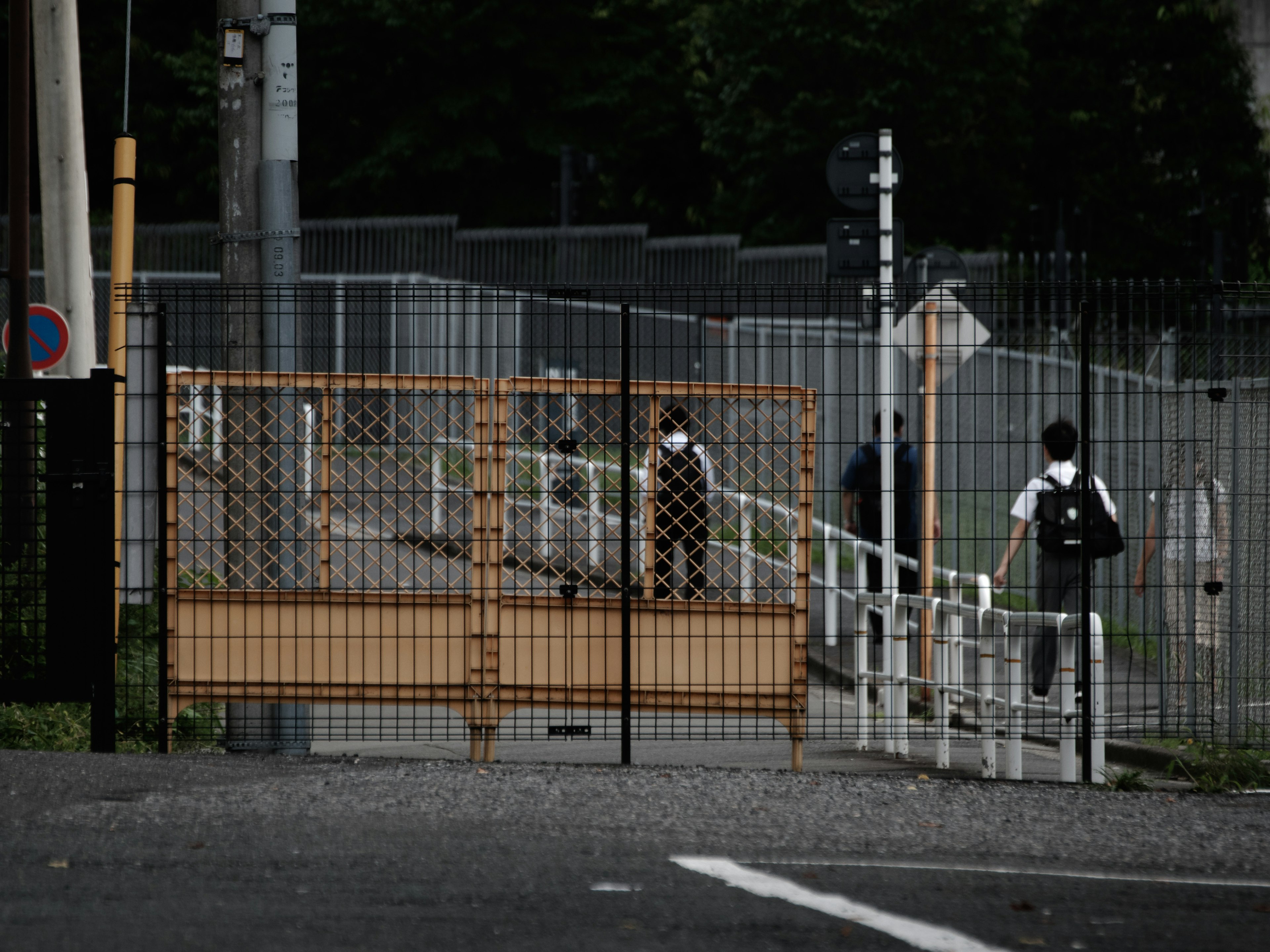 People walking along a path with a metal fence