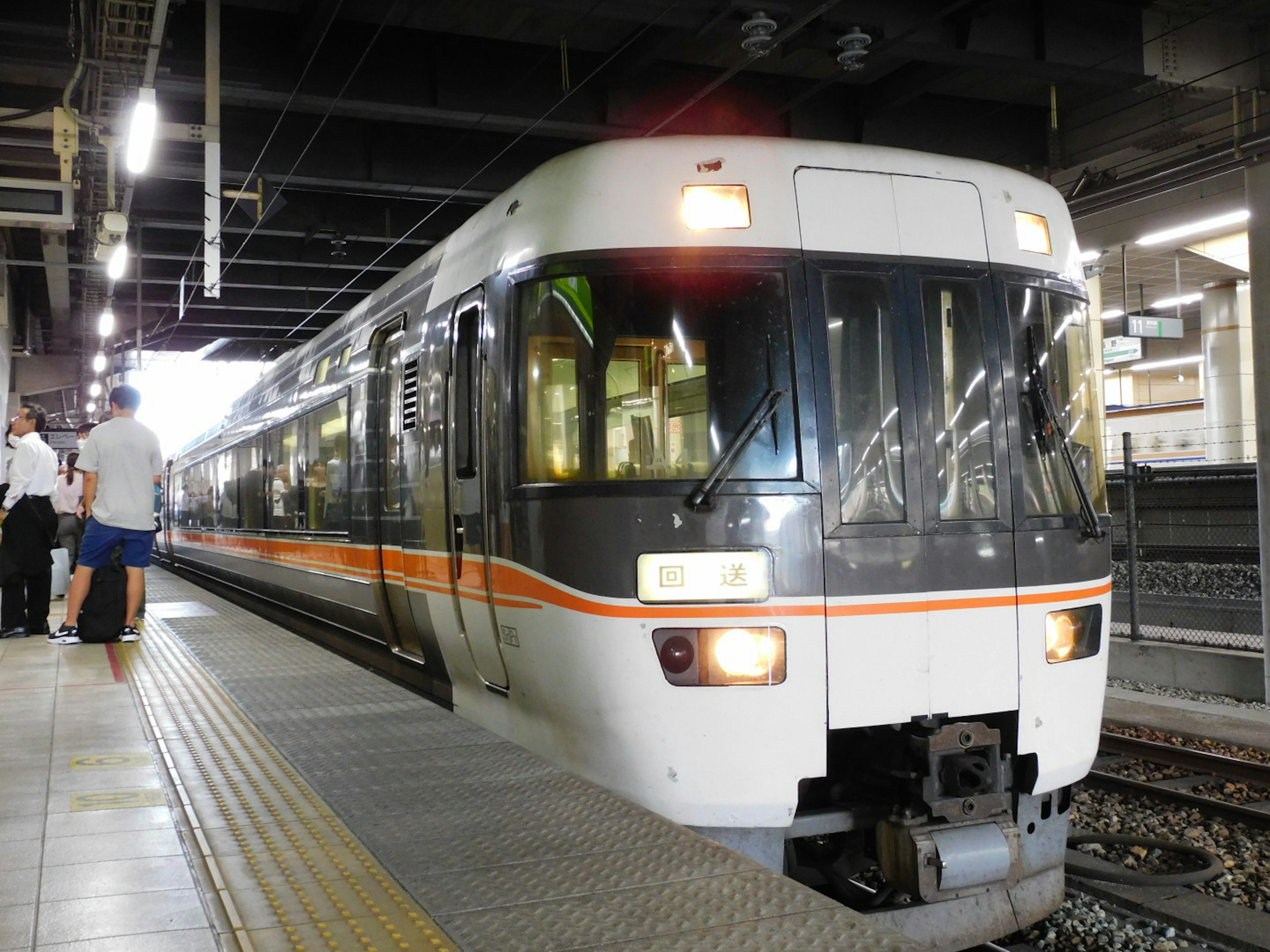 Un train blanc et orange est arrêté à une gare