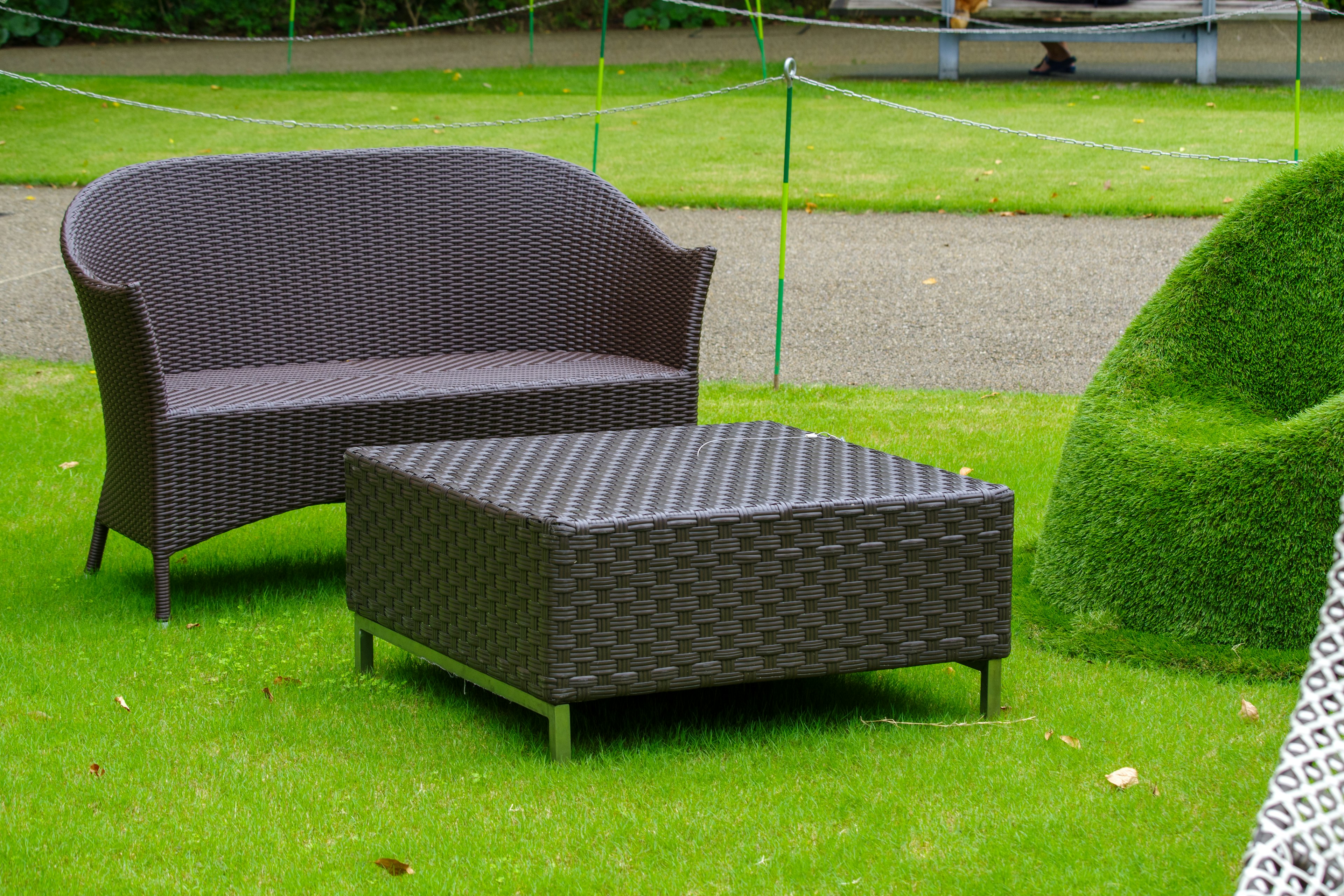 Brown wicker sofa and table placed on a lawn