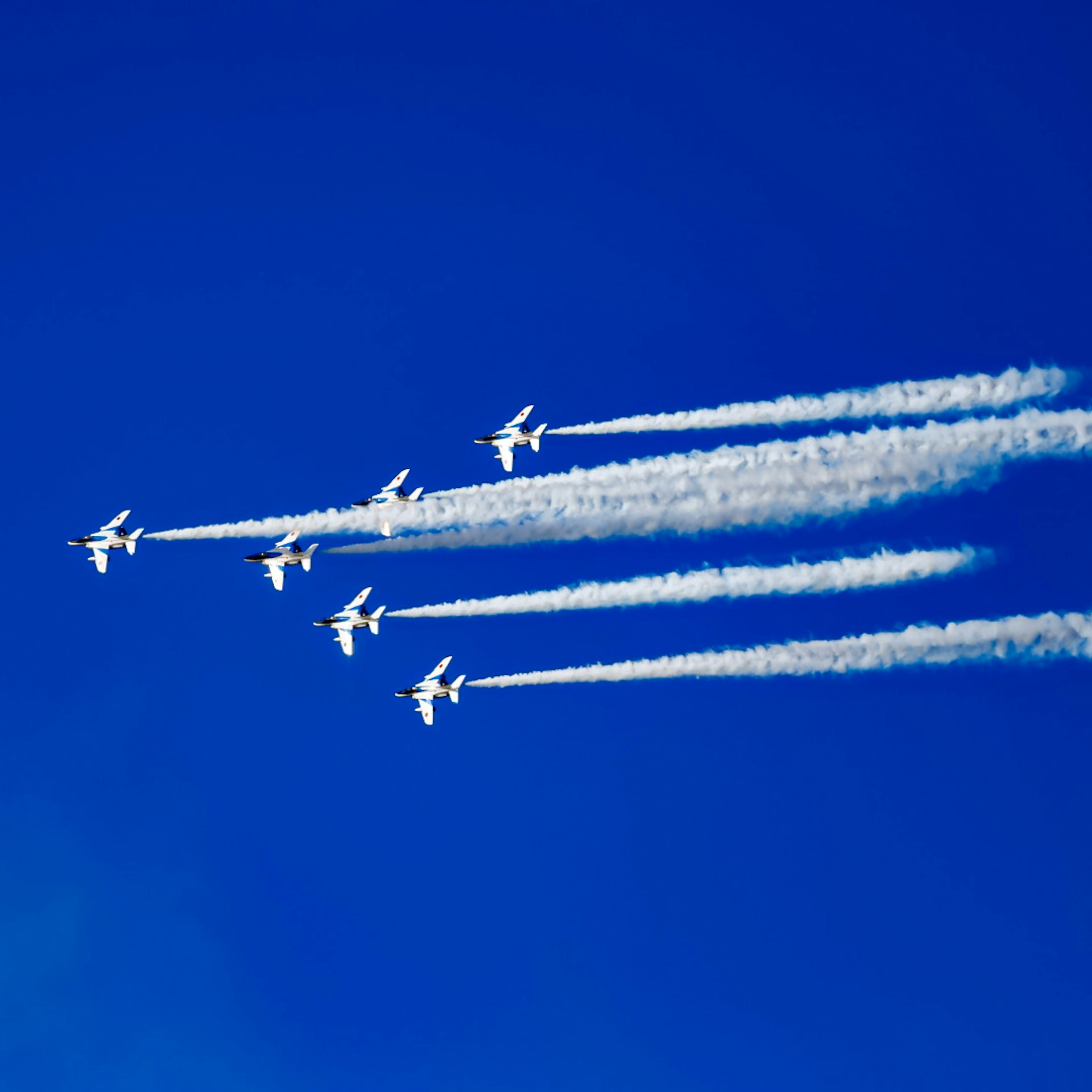 青空に飛行機が飛び交う様子と白い飛行機雲