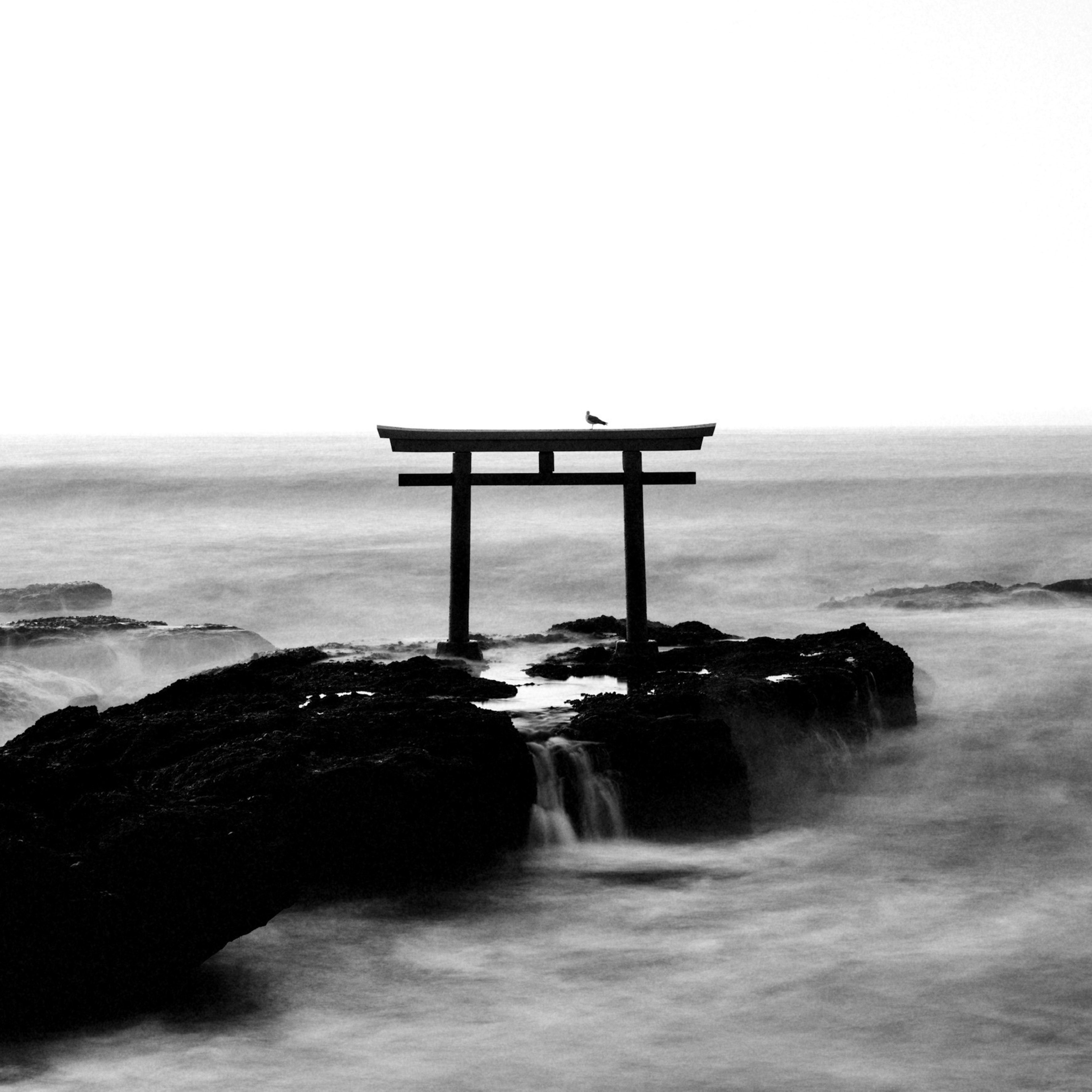 海の上に立つ鳥居のシルエットと波の流れ