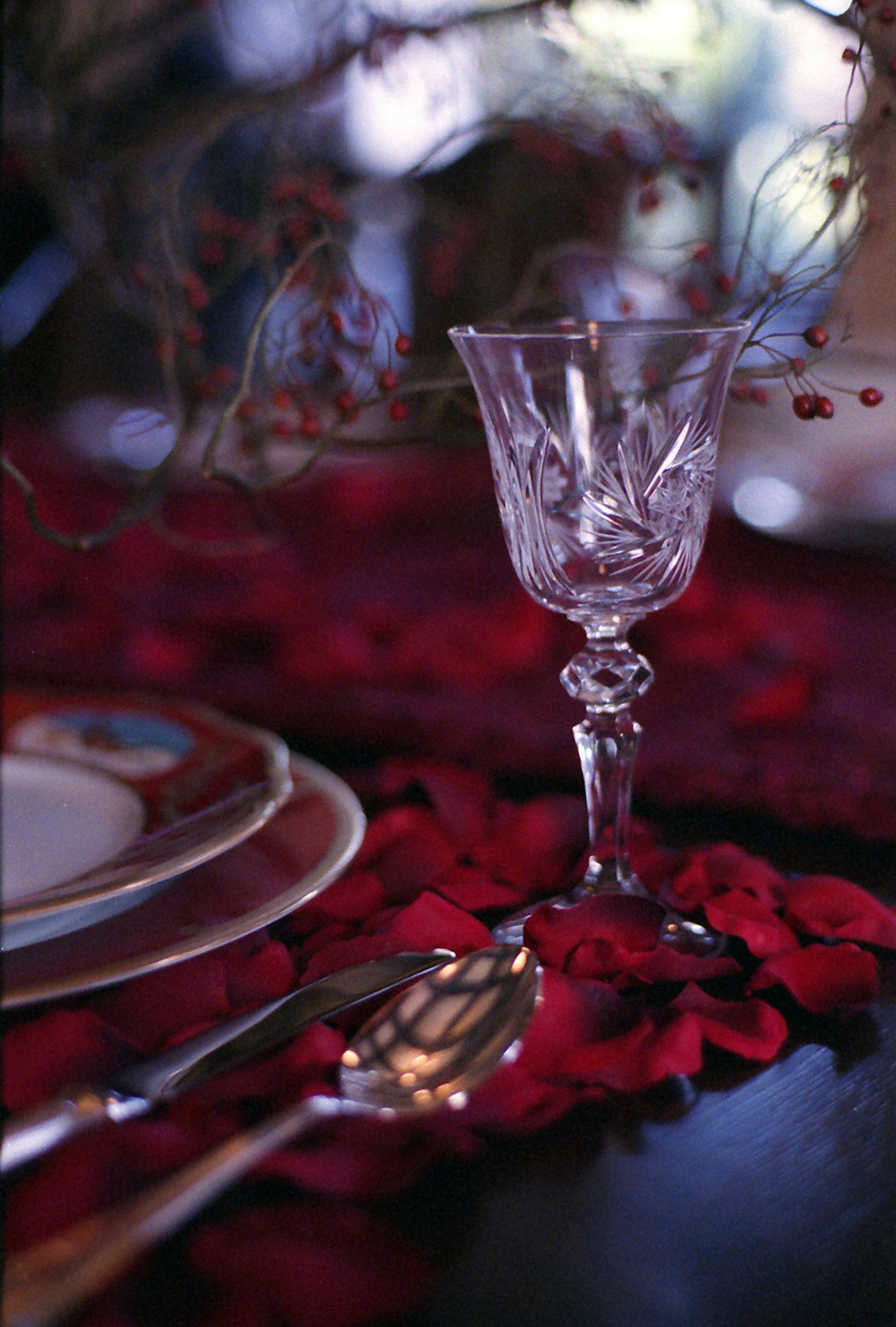 Verre en cristal et assiette sur une nappe de pétales rouges