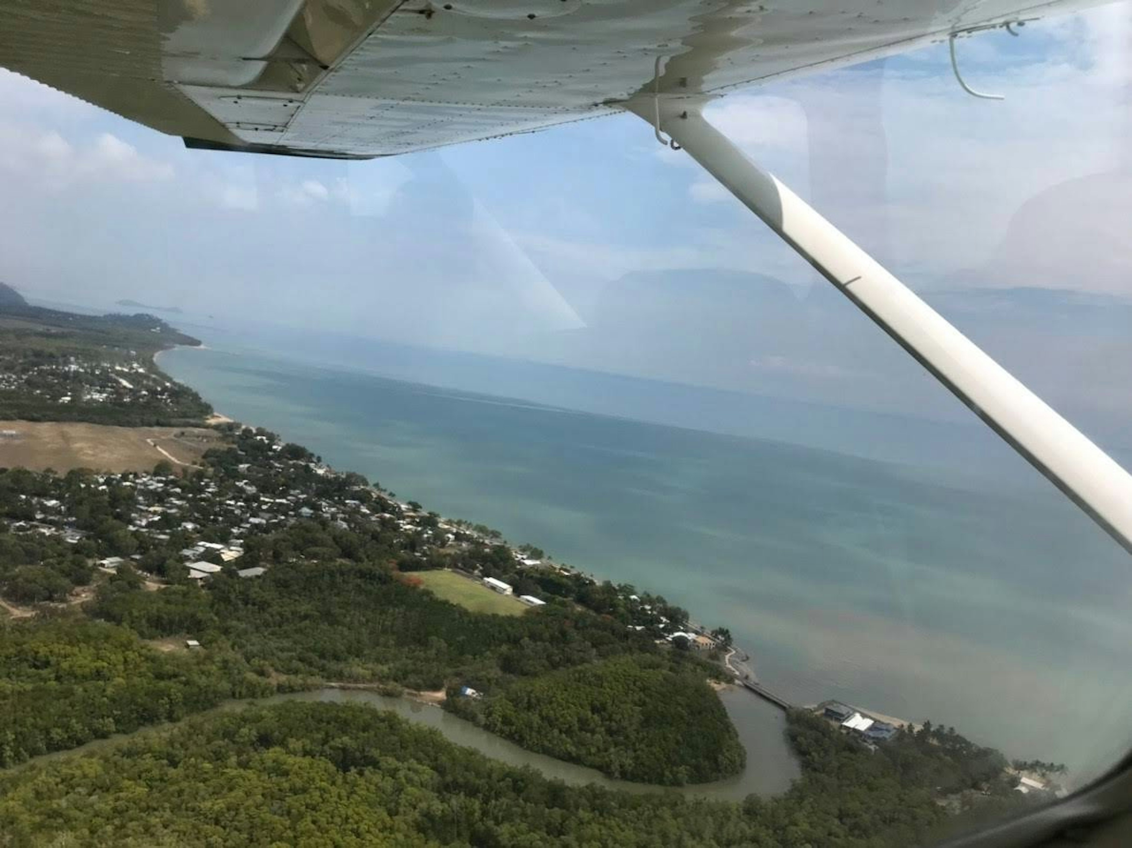 Aerial view of a coastal town featuring green landscapes and blue waters