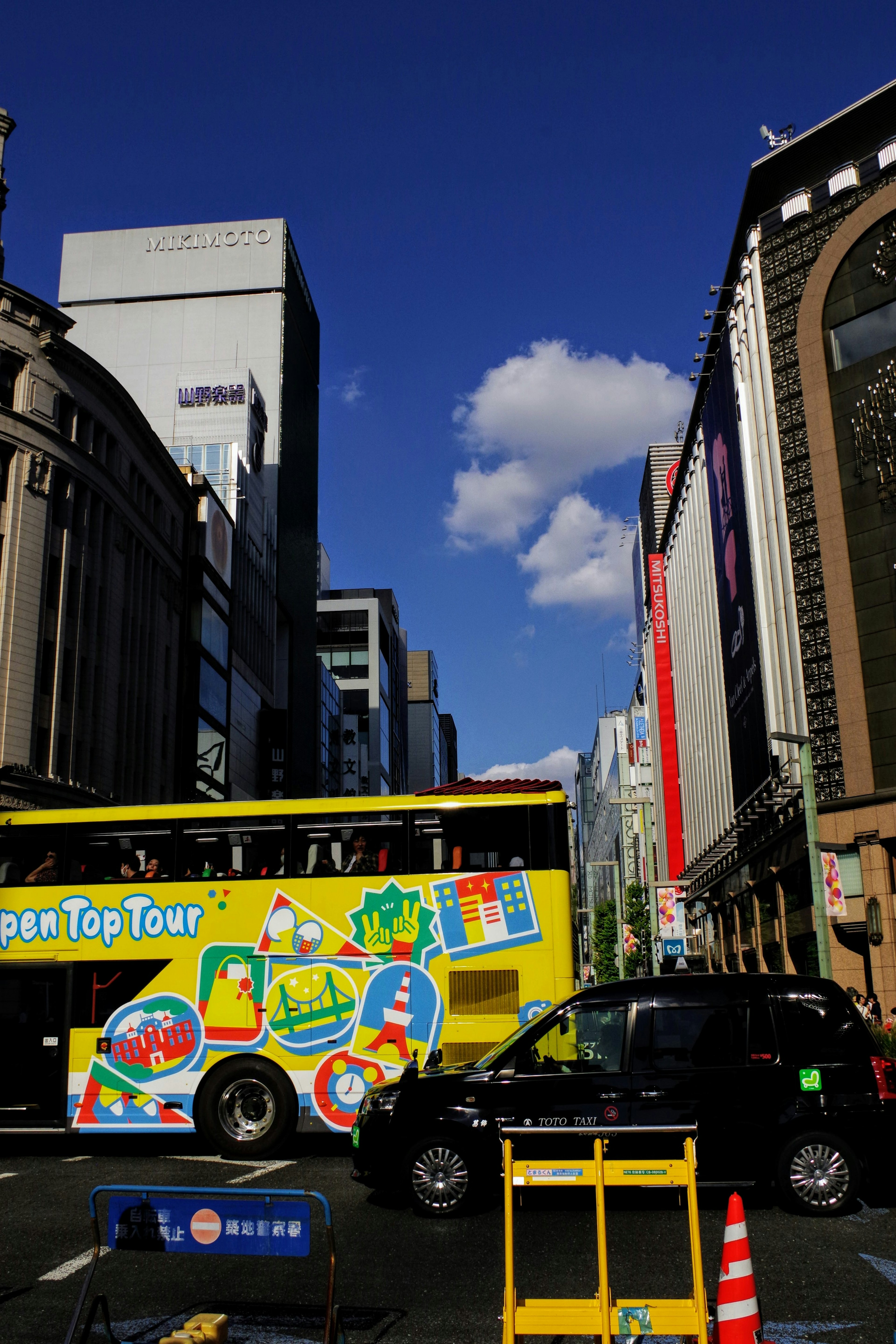 Bunter Sightseeing-Bus unter blauem Himmel mit Stadtlandschaft