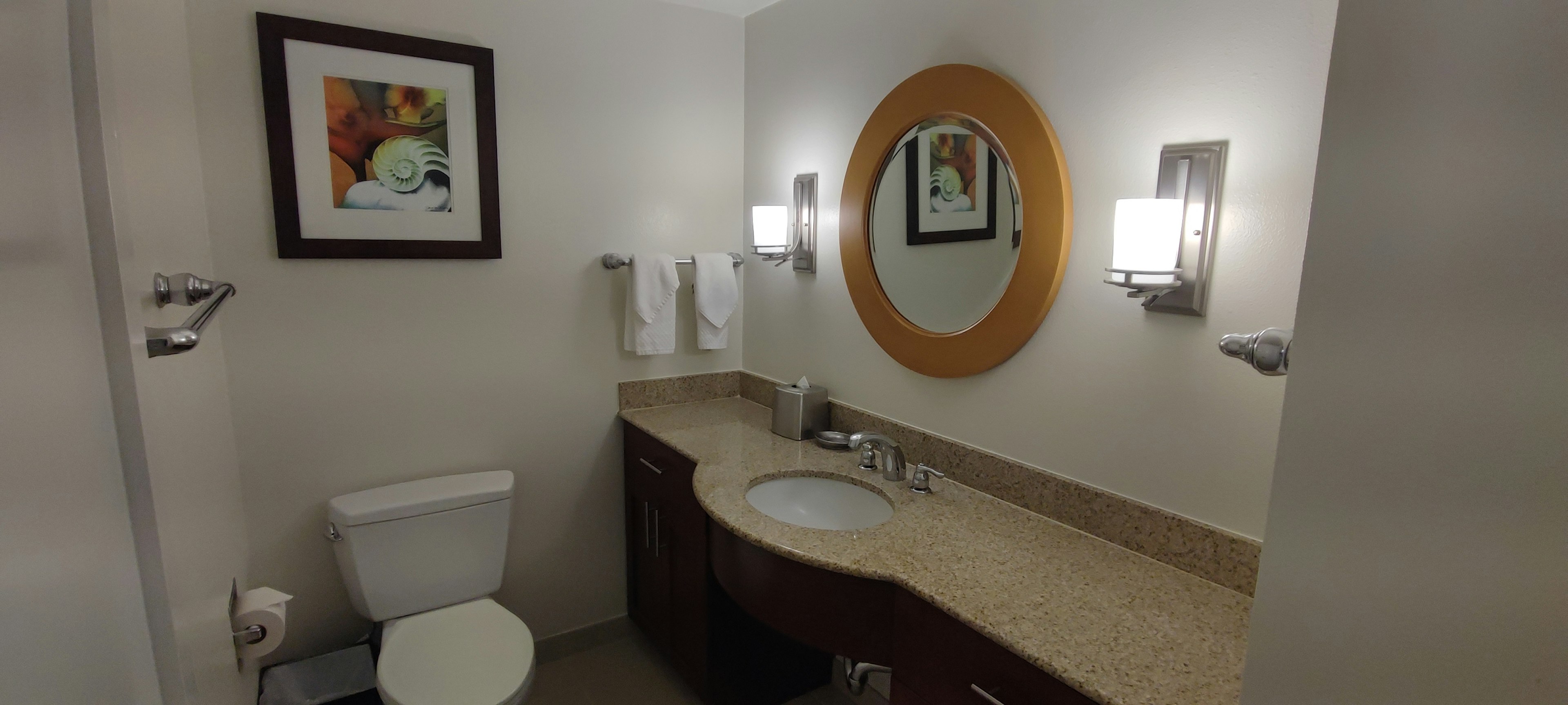 Bright bathroom featuring a round mirror towels and wall art