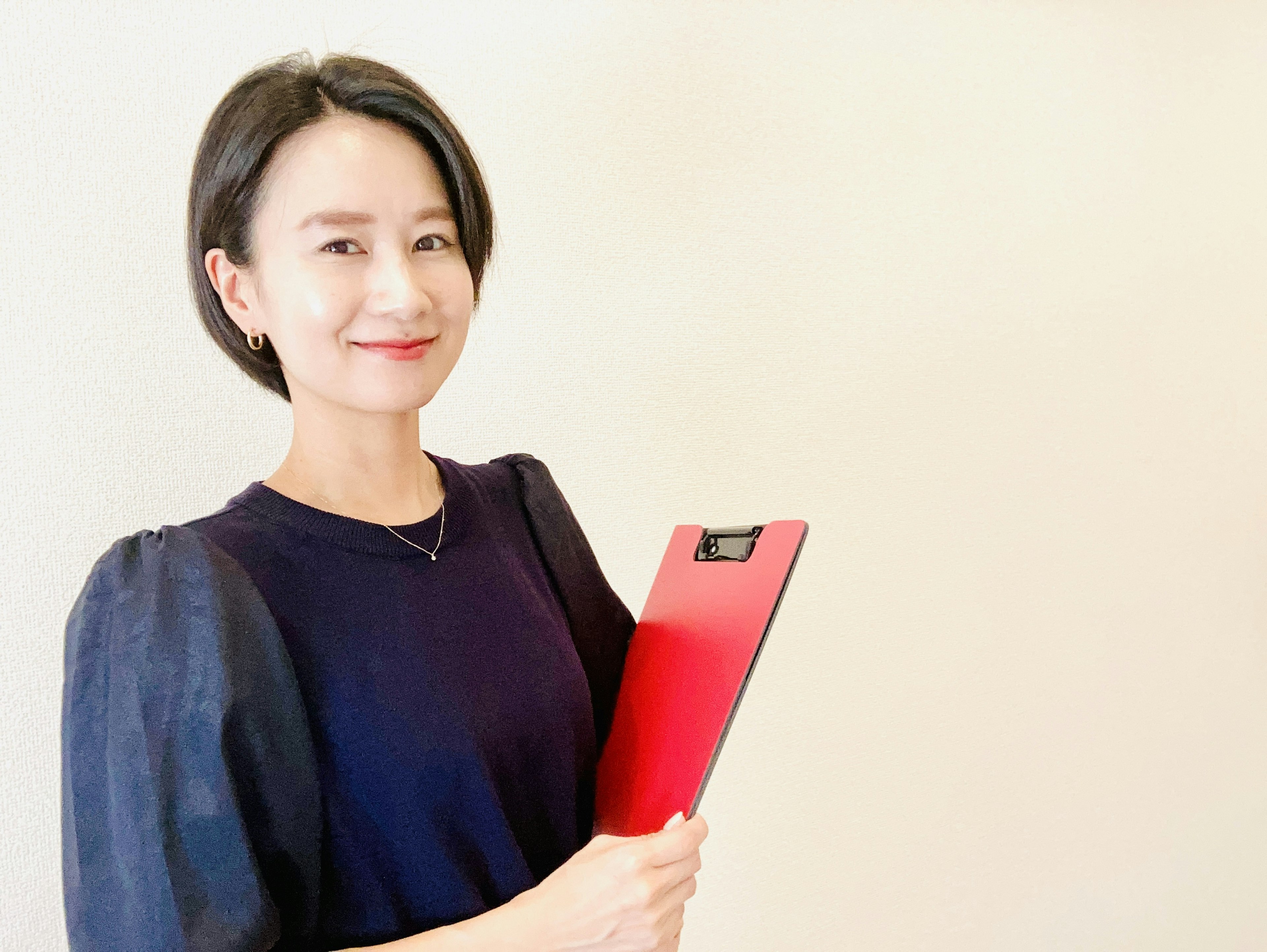 A woman smiling while holding a red folder