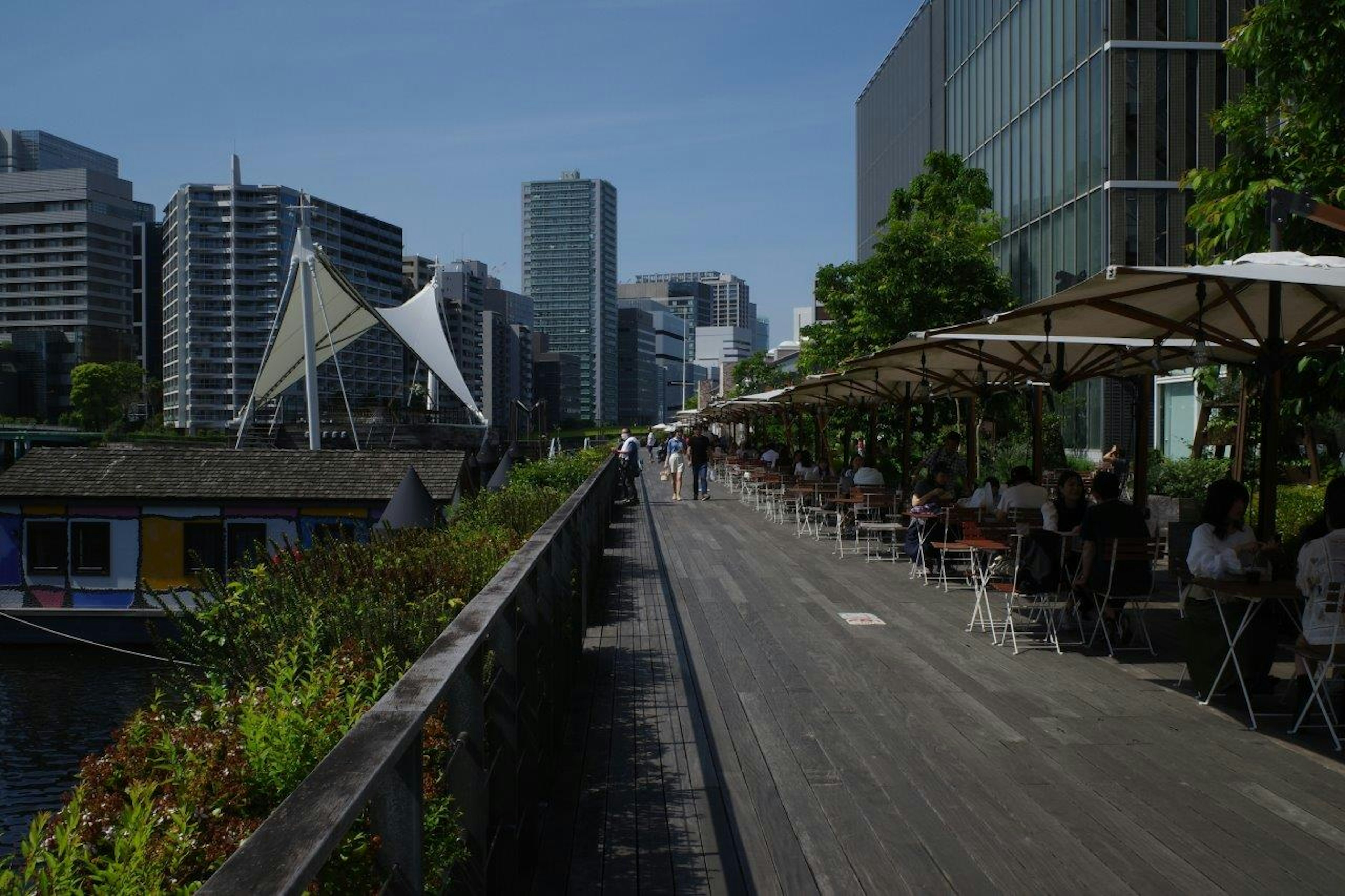 Urban walkway featuring café terraces and high-rise buildings