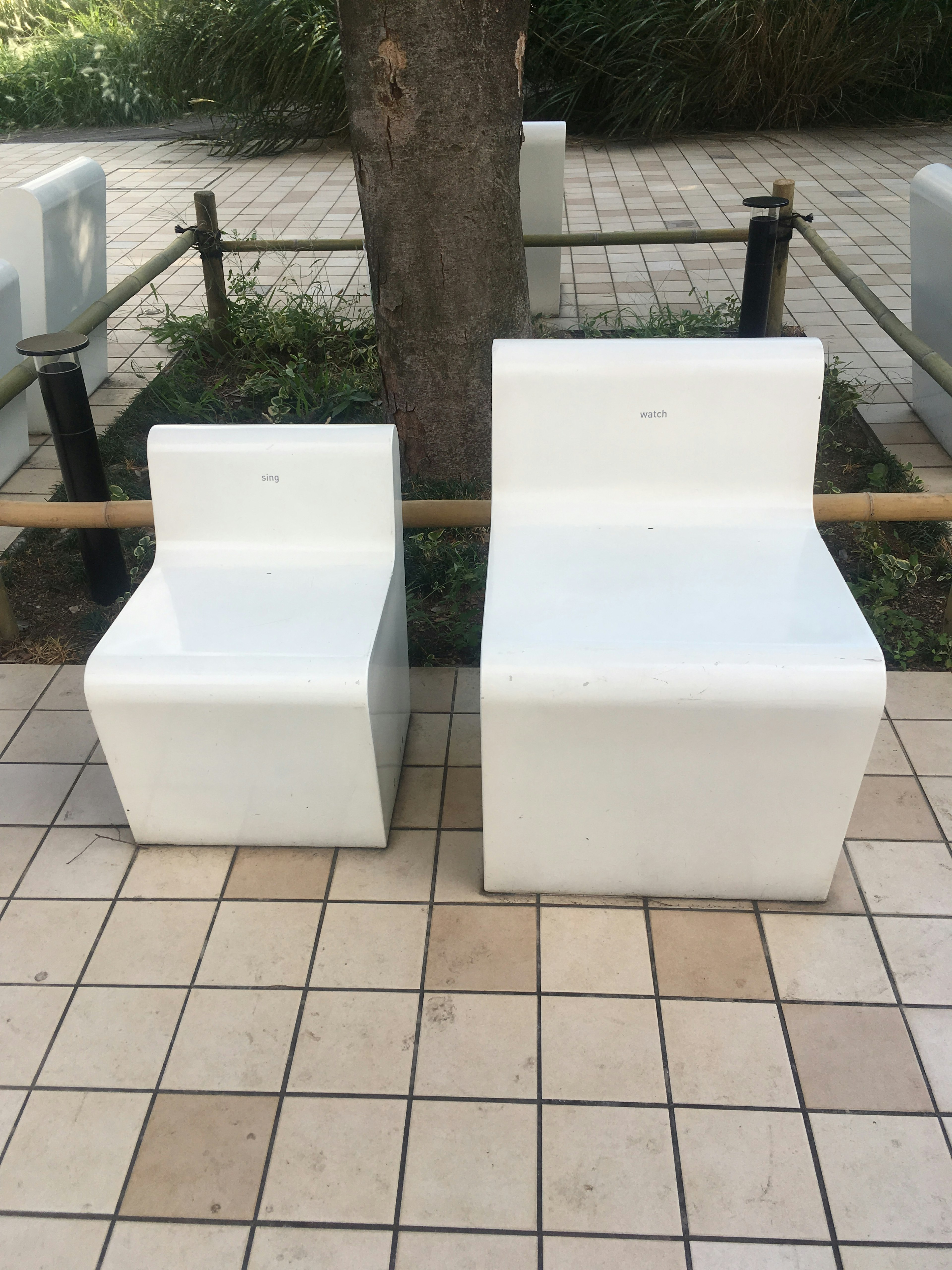 Deux chaises blanches modernes au design minimaliste posées sur un pavé carrelé