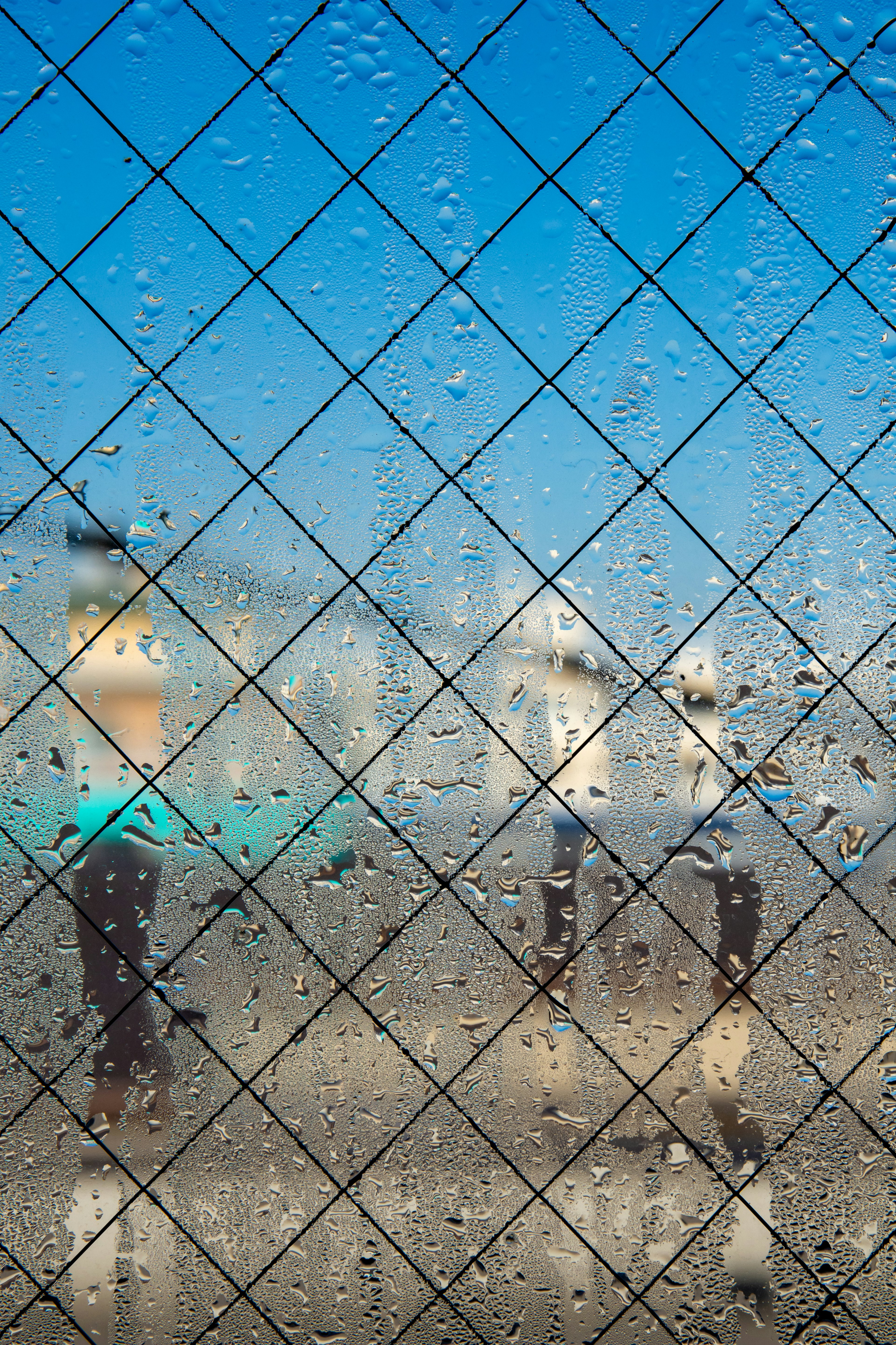 View through a rain-dropped window with a blue sky