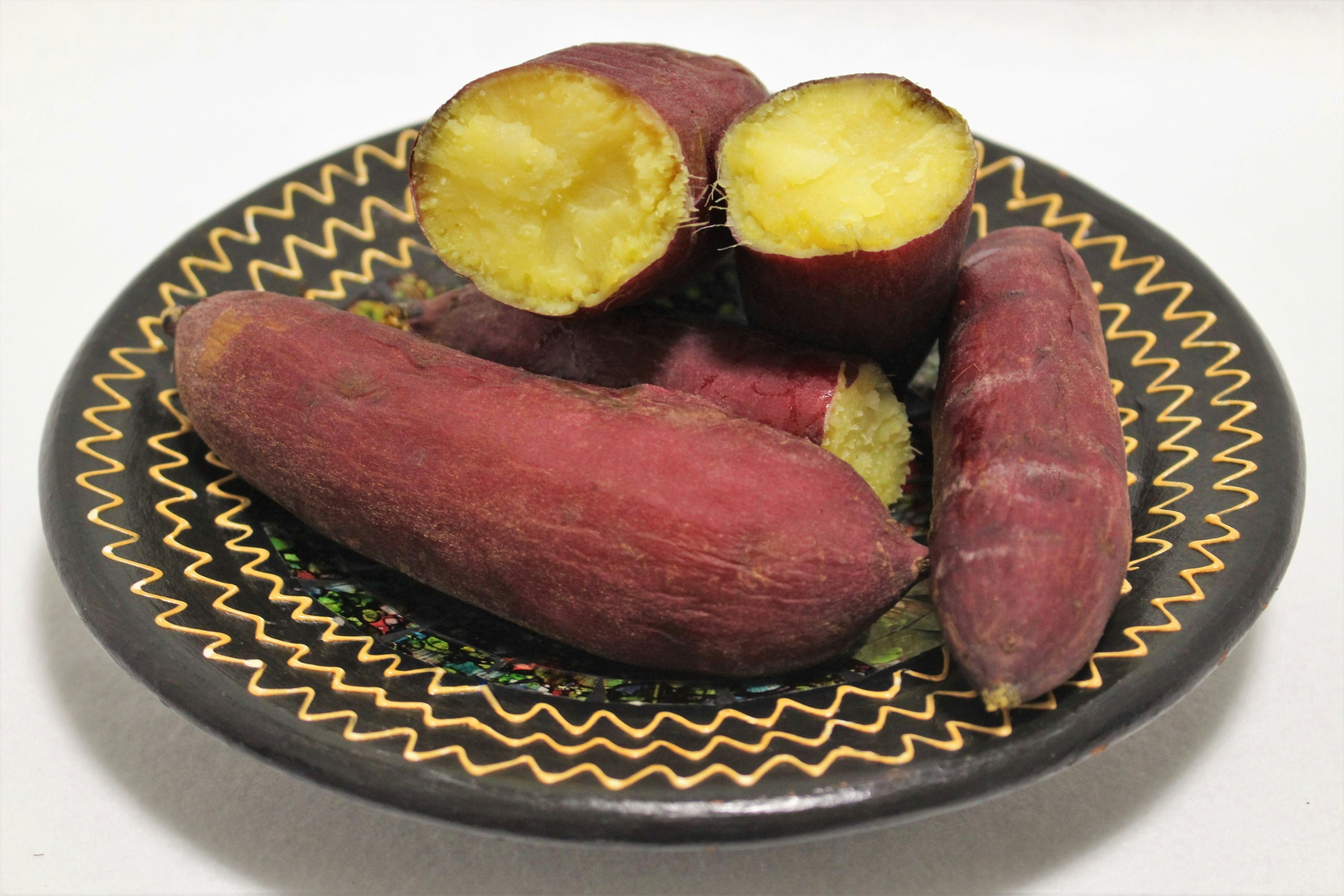 Plato decorativo con batatas moradas y una cortada