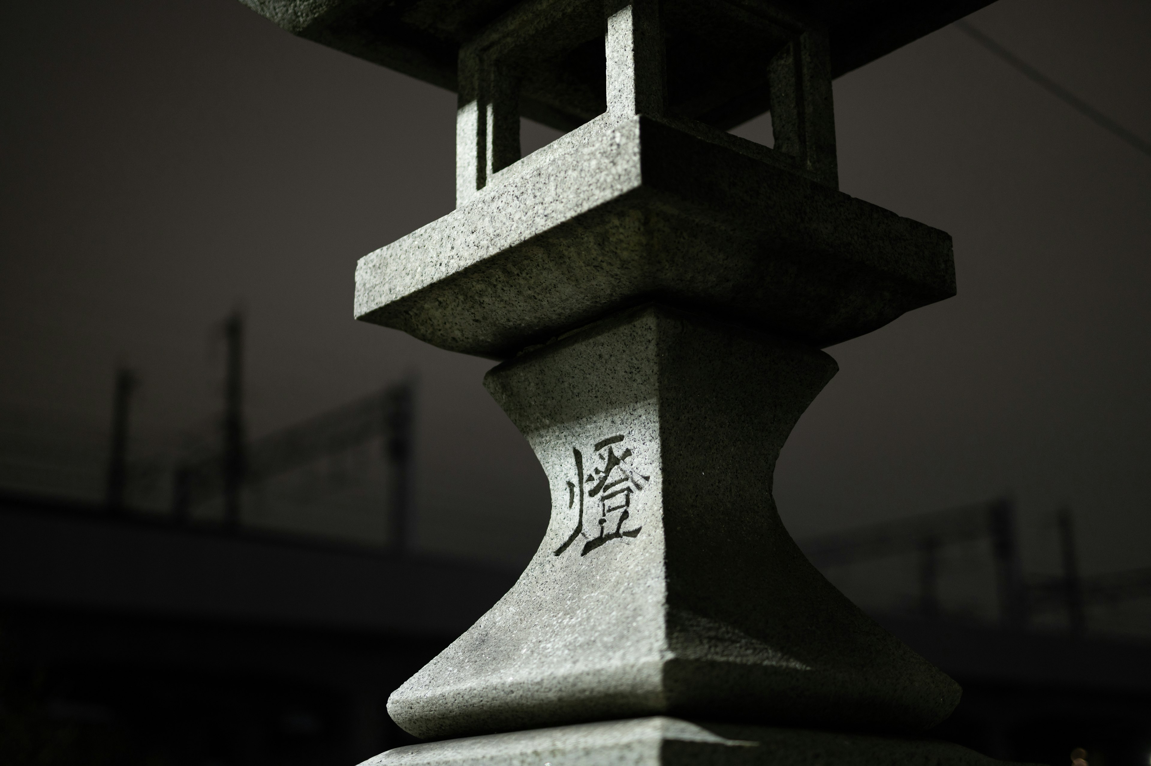 Close-up shot of a stone lantern with Japanese characters visible against a dark background