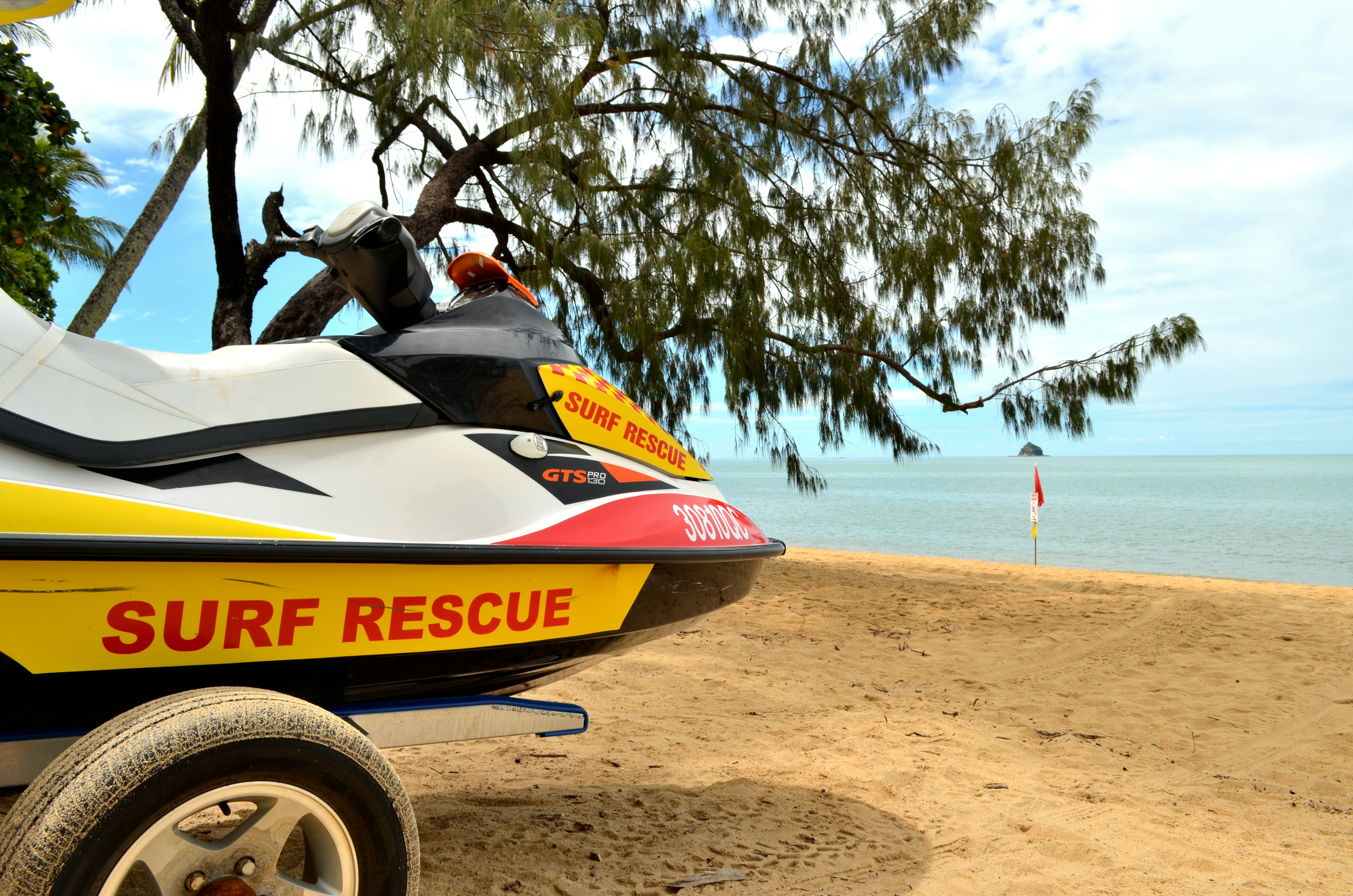 Surf rescue jet ski on the beach with trees and calm sea in the background