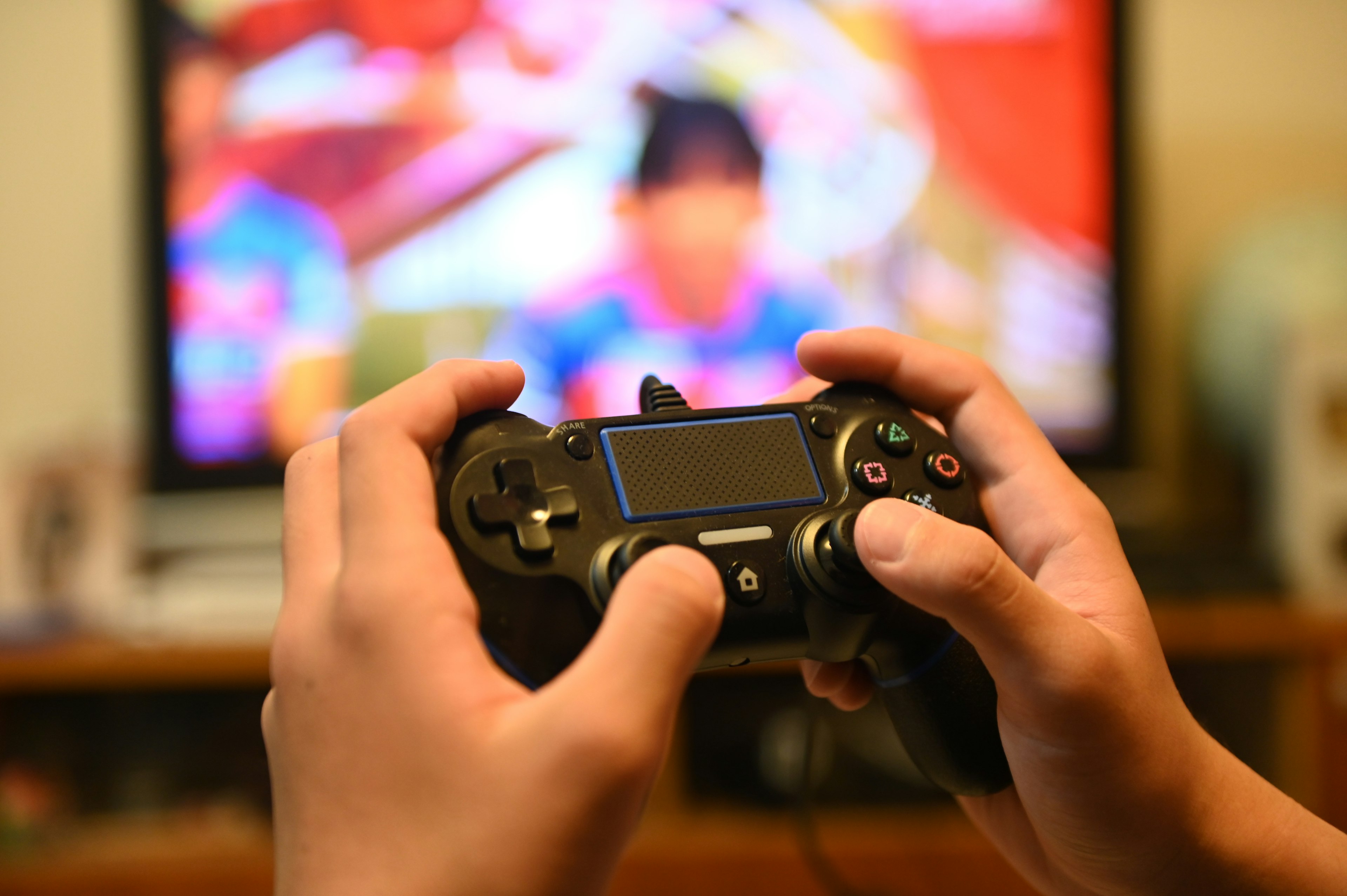 Hands holding a game controller with a television screen in the background