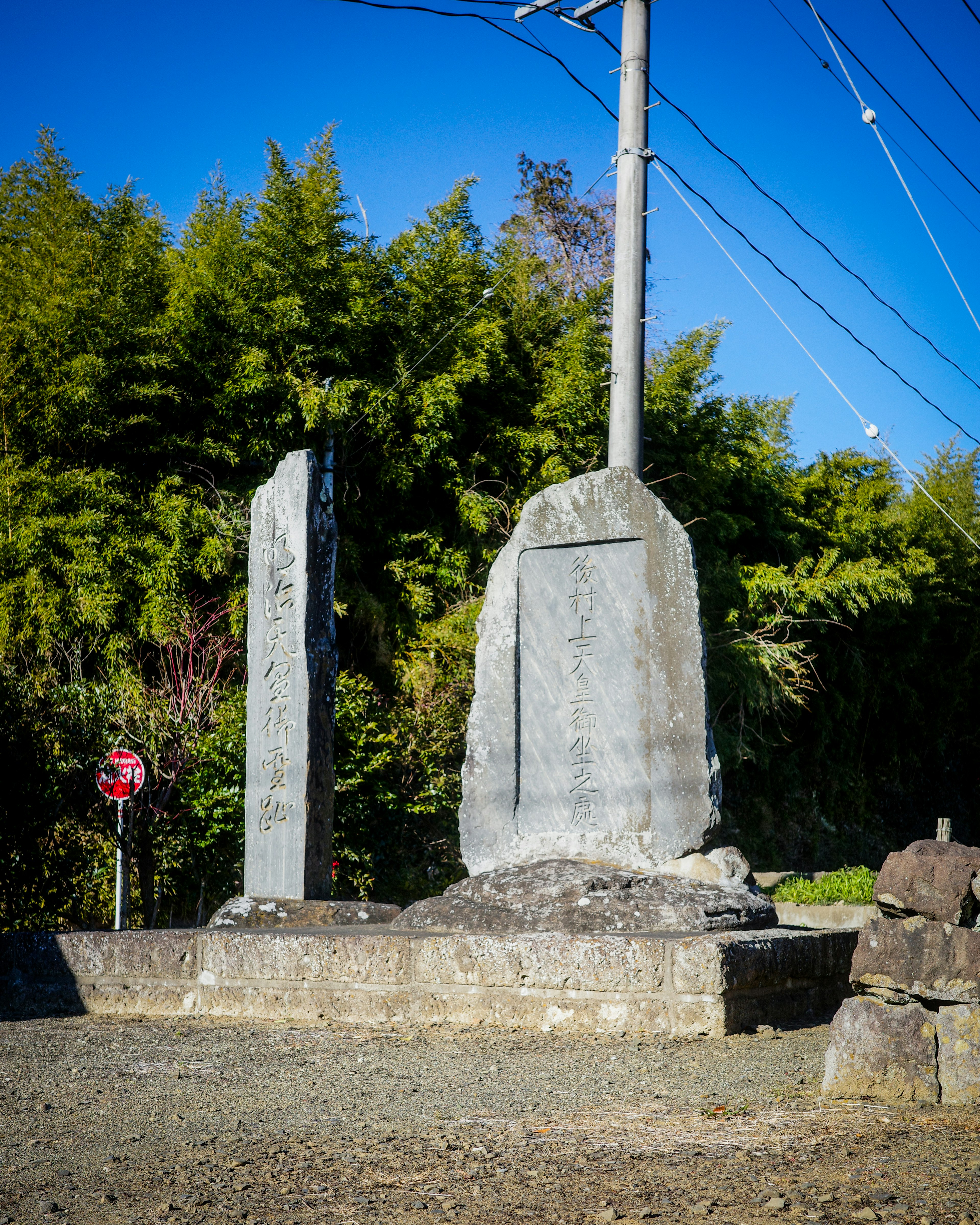 Deux grands monuments en pierre se tenant dans un paysage Entourés de bambous et d'un poteau électrique