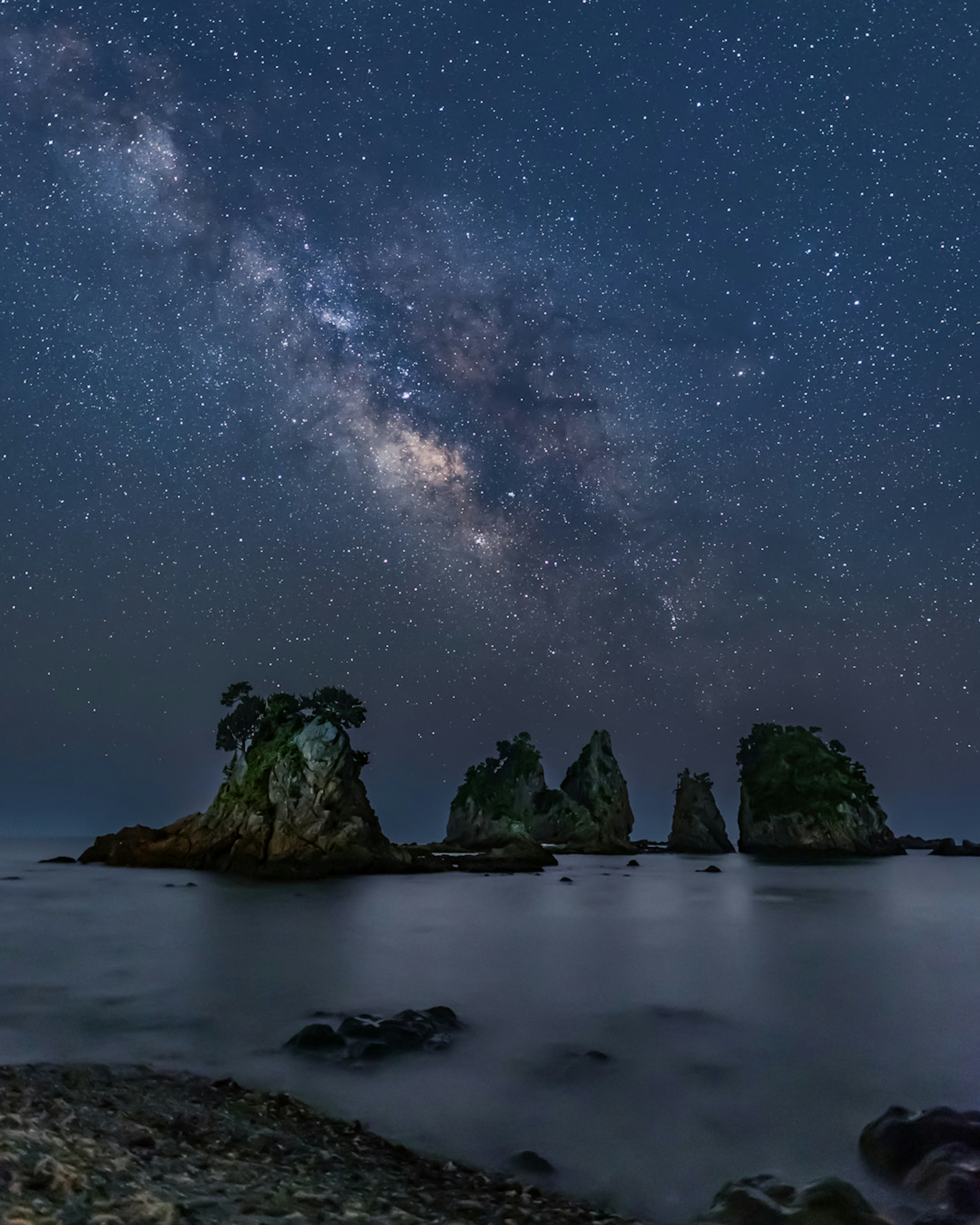 Formazioni rocciose sotto un cielo stellato con la Via Lattea