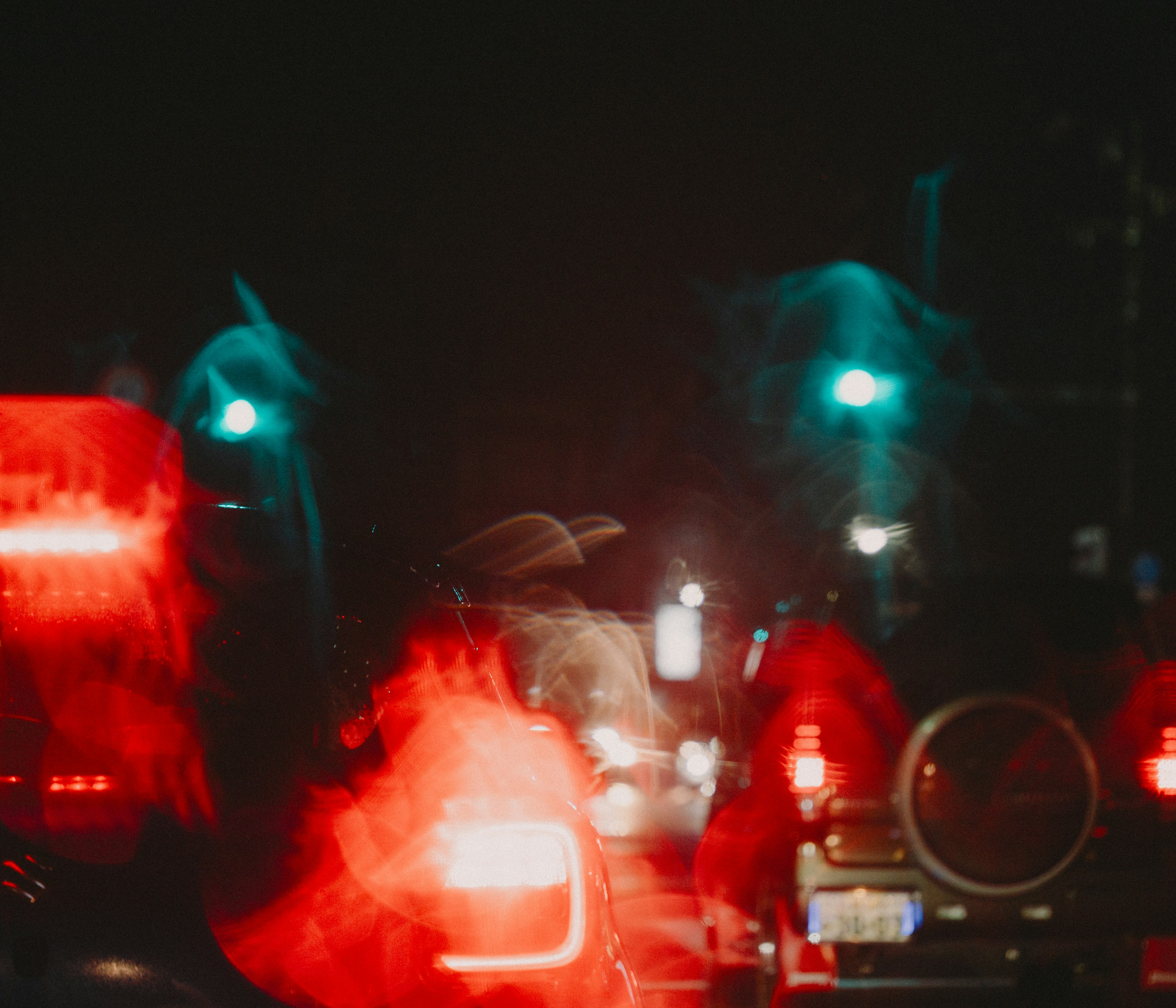 Imagen borrosa de tráfico nocturno con señales rojas y verdes iluminadas