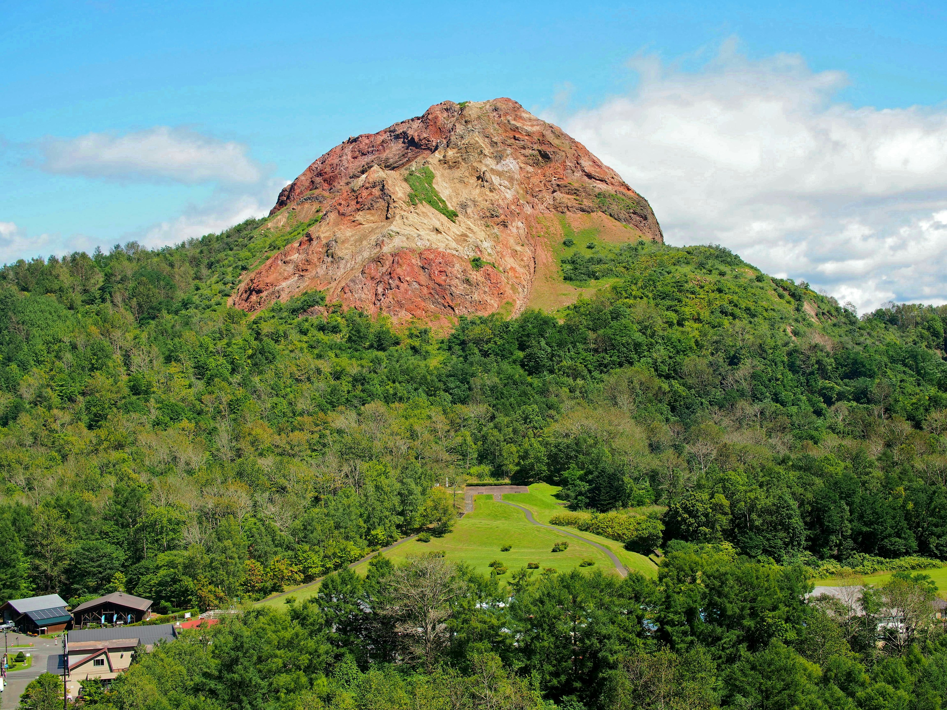 Pemandangan gunung batu merah dikelilingi hutan hijau