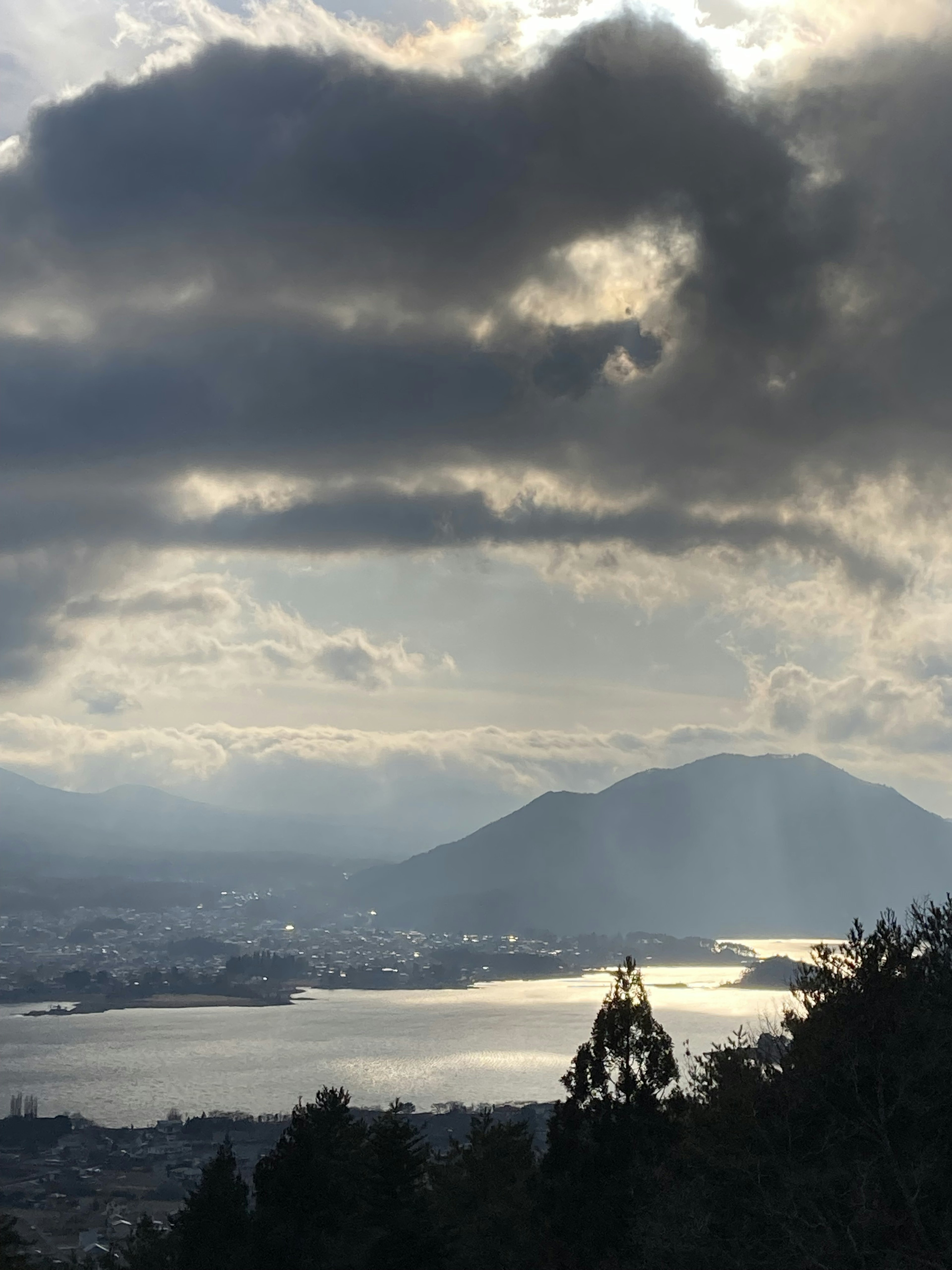 山和湖的風景，陰雲密布的天空，陽光透過雲層