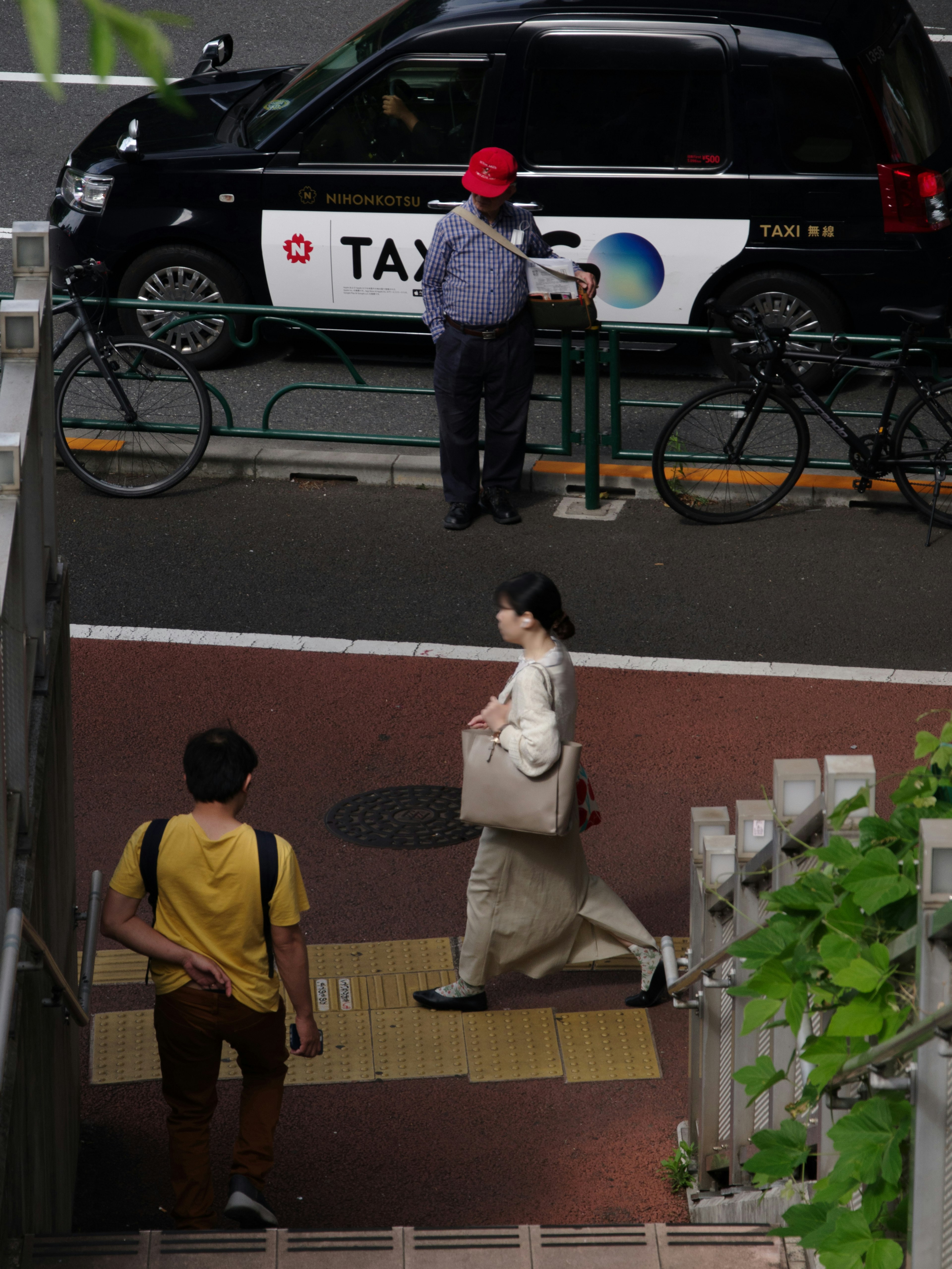 一名女性走在出租车附近，附近停着自行车