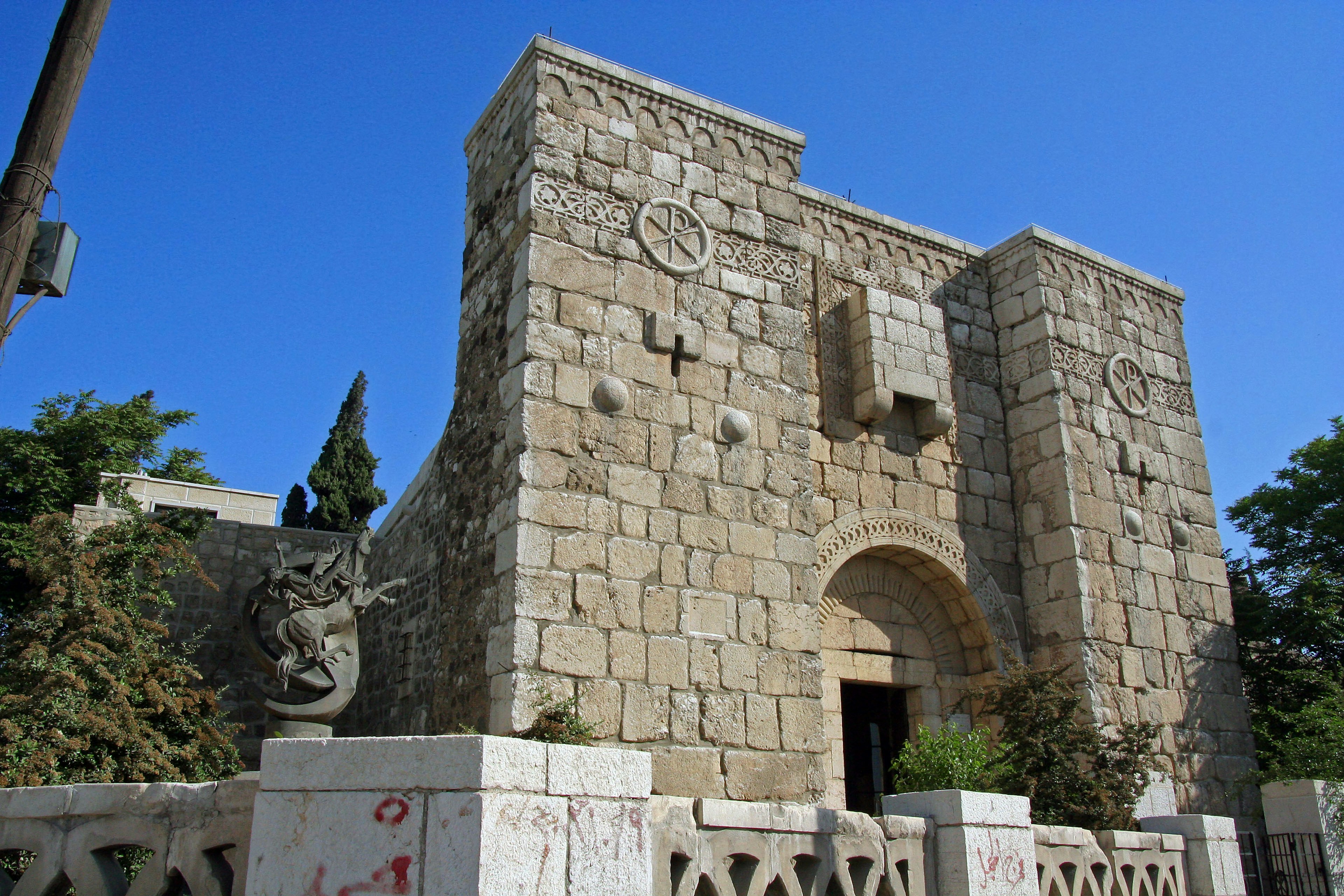 Edificio in pietra antica con elementi architettonici unici e vegetazione